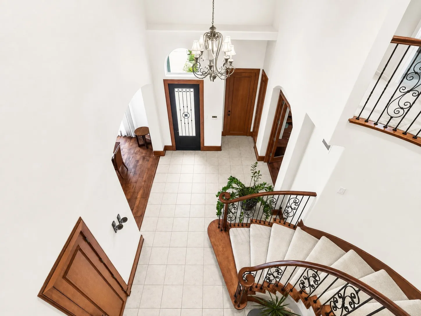 Two-story foyer with a curved staircase, wrought iron balusters, and wood-finish handrails