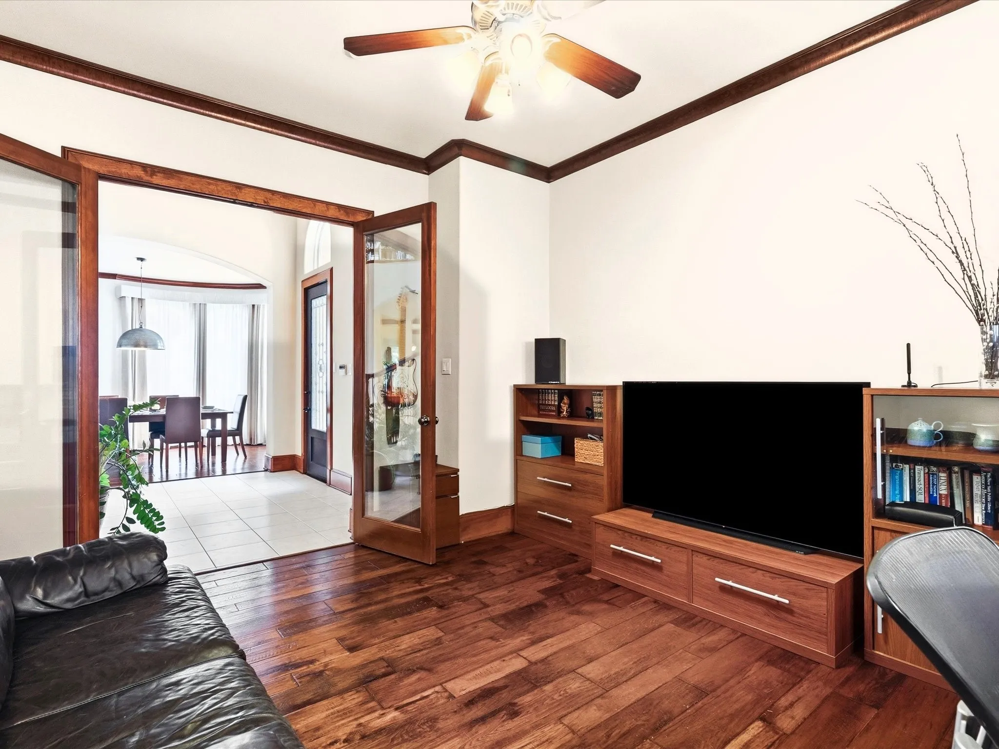Office featuring glass French door, rich wood-finish flooring, a ceiling fan with integrated lighting, and crown molding