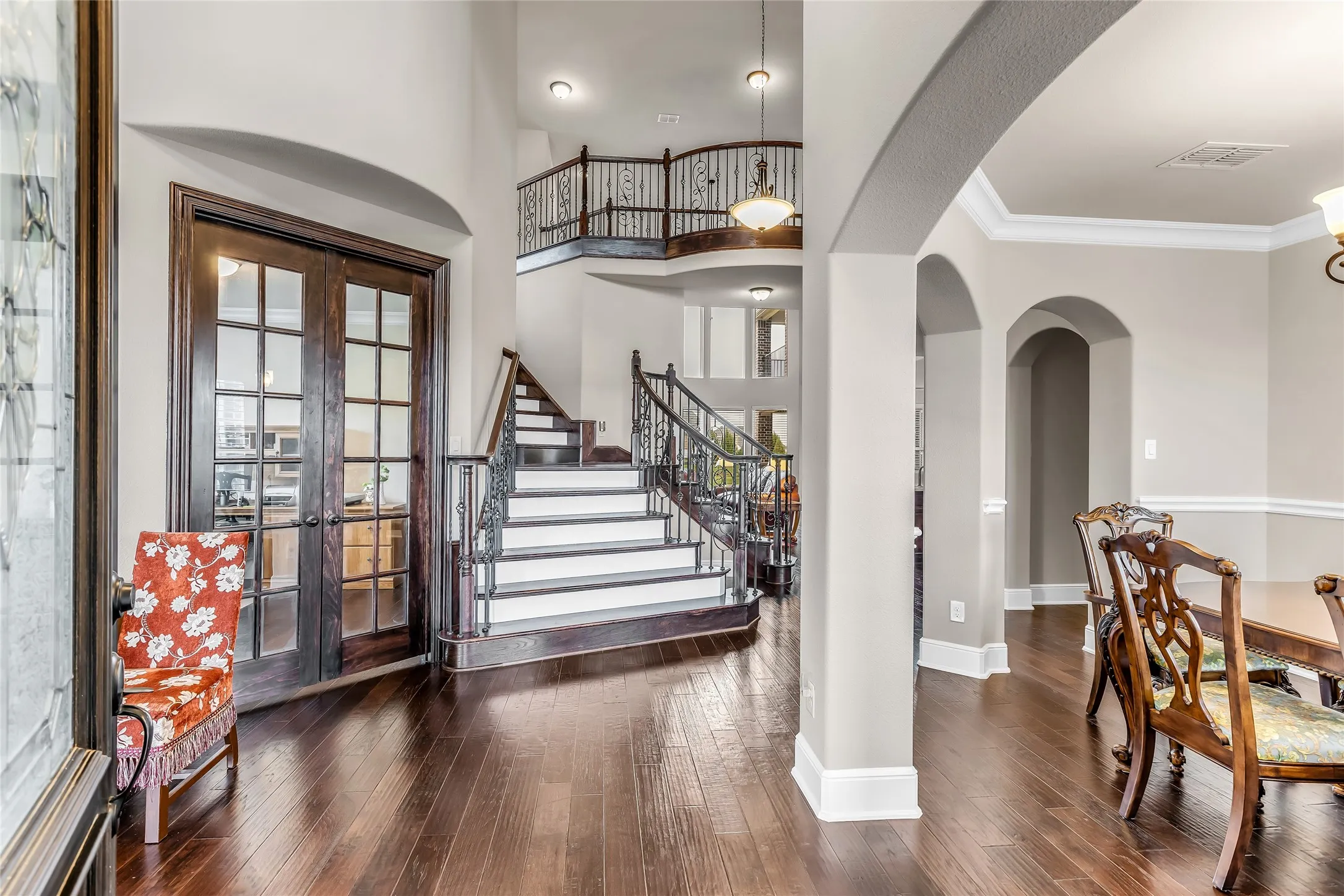 Grand entry featuring rich wood-finish flooring, an elegant staircase with wrought iron balusters, and a second-story landing with matching railing