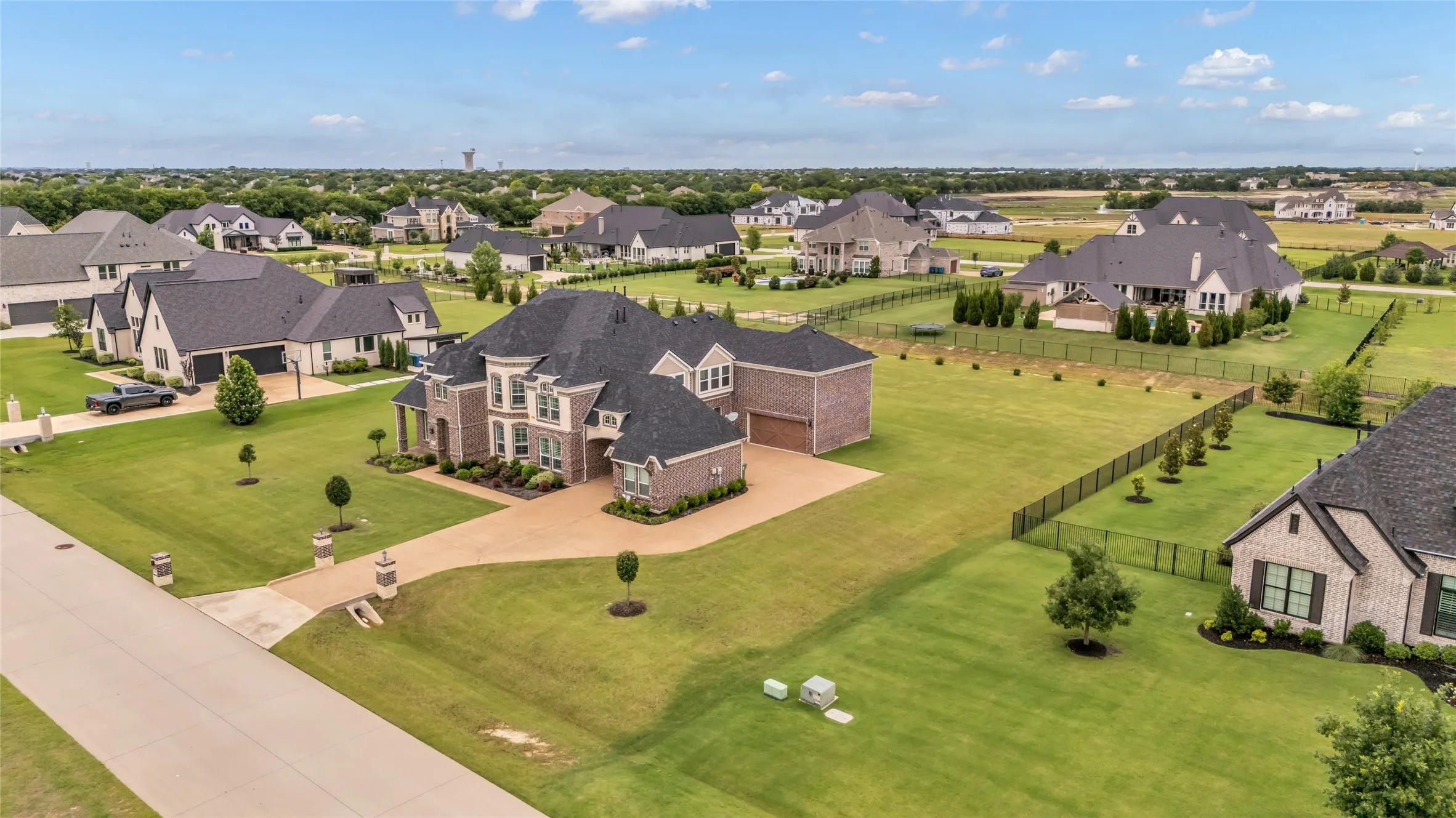 Expansive residential property featuring a brick and stone facade, a multi-car garage, and a large manicured lawn