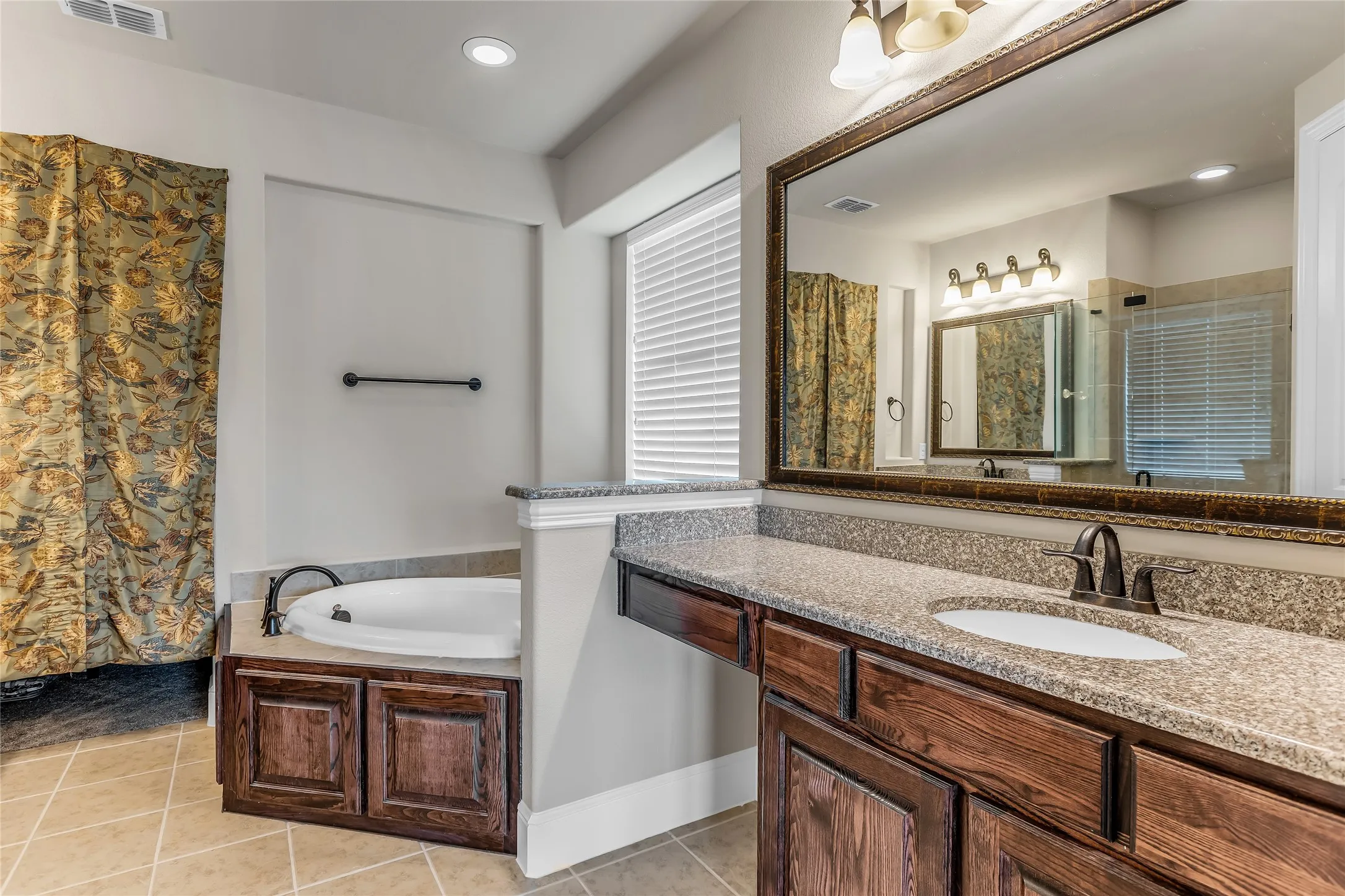 Bathroom featuring a large vanity with a granite-style countertop, integrated sink, and an expansive framed mirror