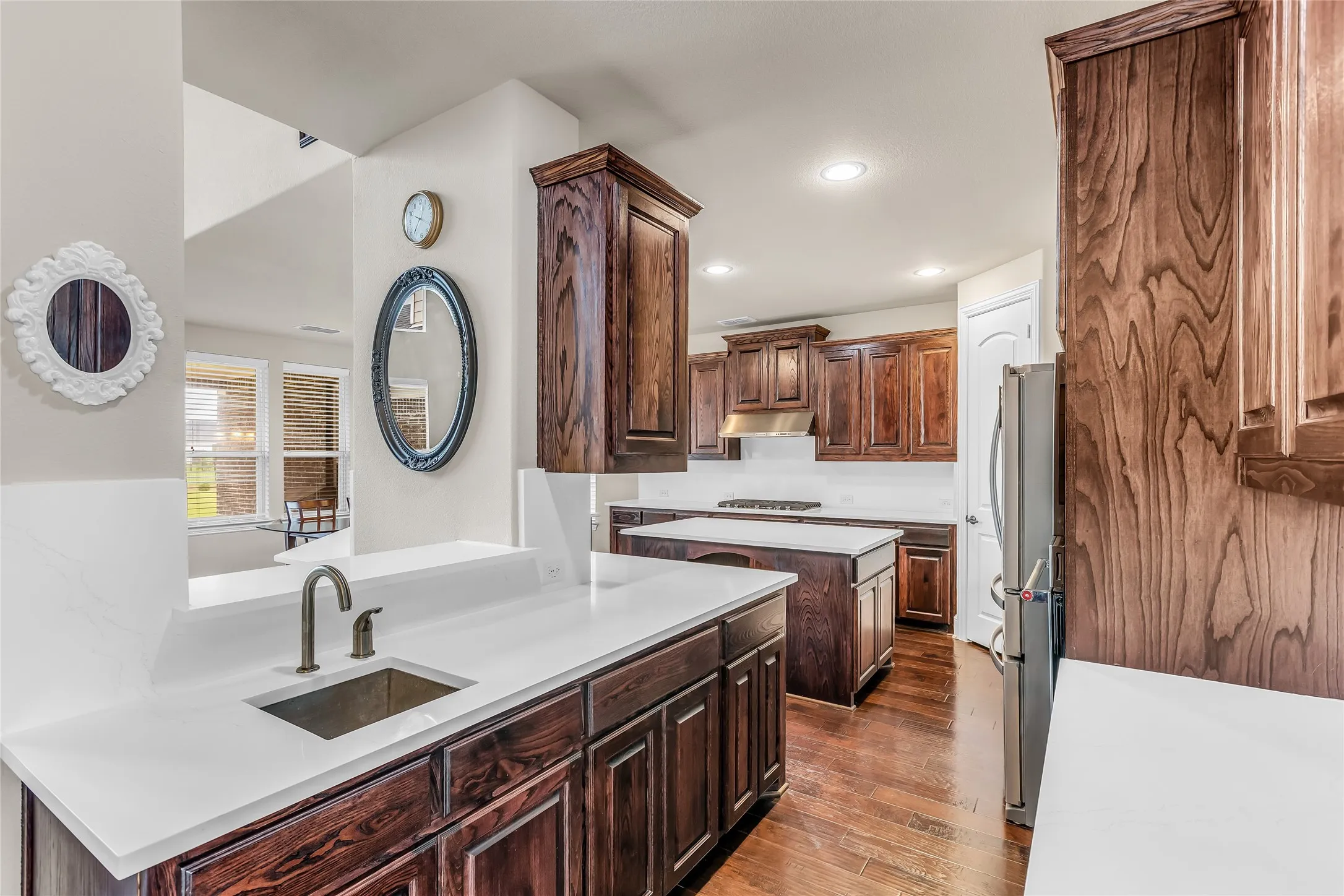 Kitchen featuring wood-finish cabinetry, white countertops, and a bronze-finish faucet