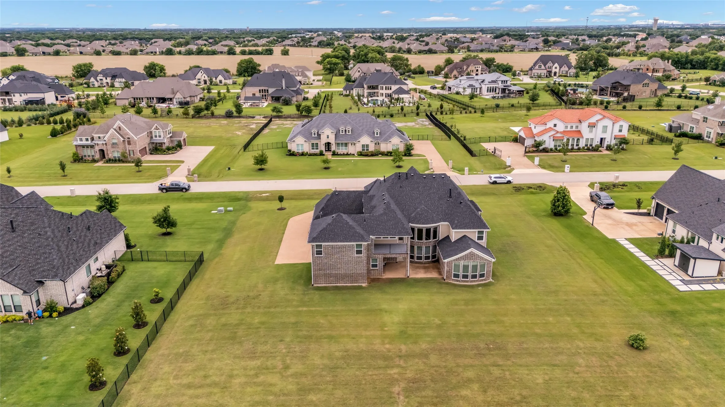 Expansive property featuring a large brick exterior home with a multi-level roofline, prominent bay windows, and a generous grassy lot