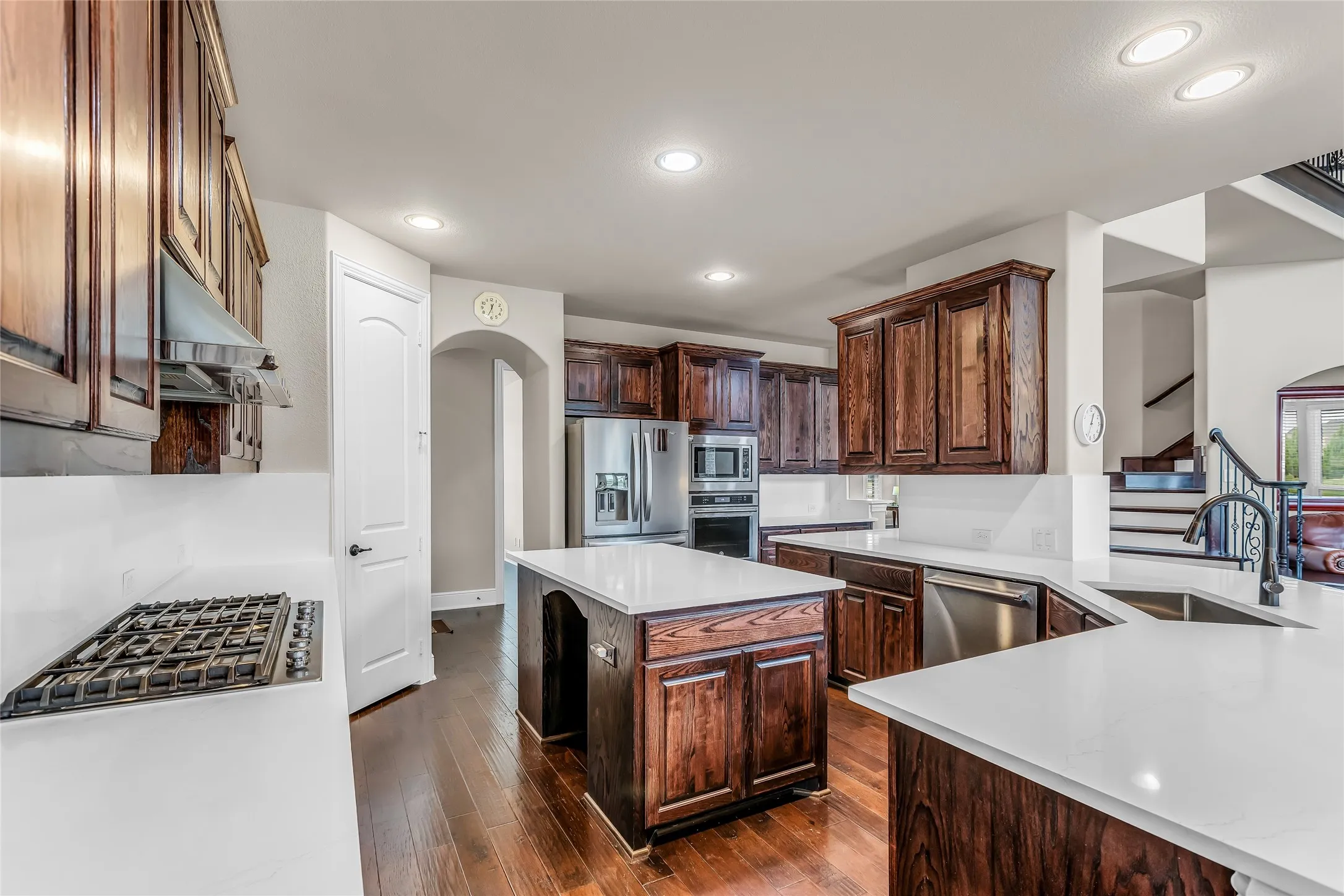 Kitchen featuring wood-finish flooring, white countertops, dark wood cabinetry, a central island, and stainless steel appliances