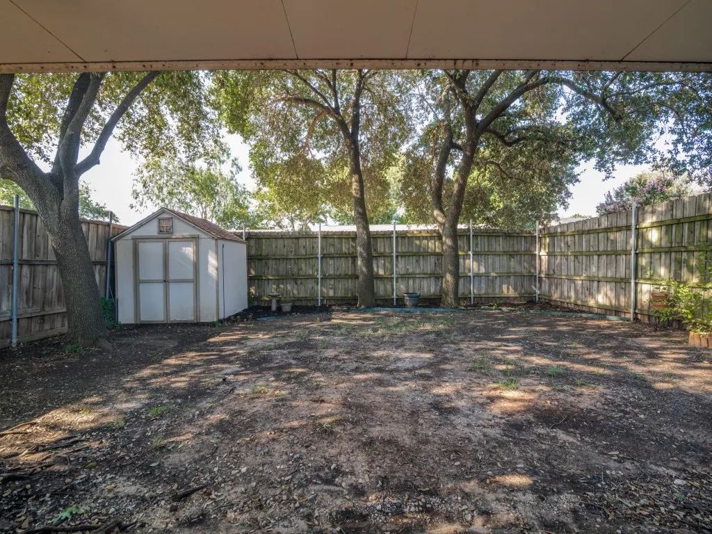 Shaded back yard with storage shed and privacy fence.