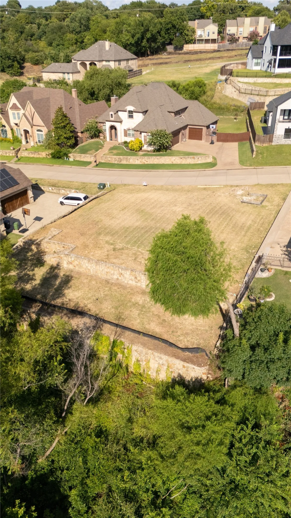 Level lot featuring a graded surface and natural stone retaining walls