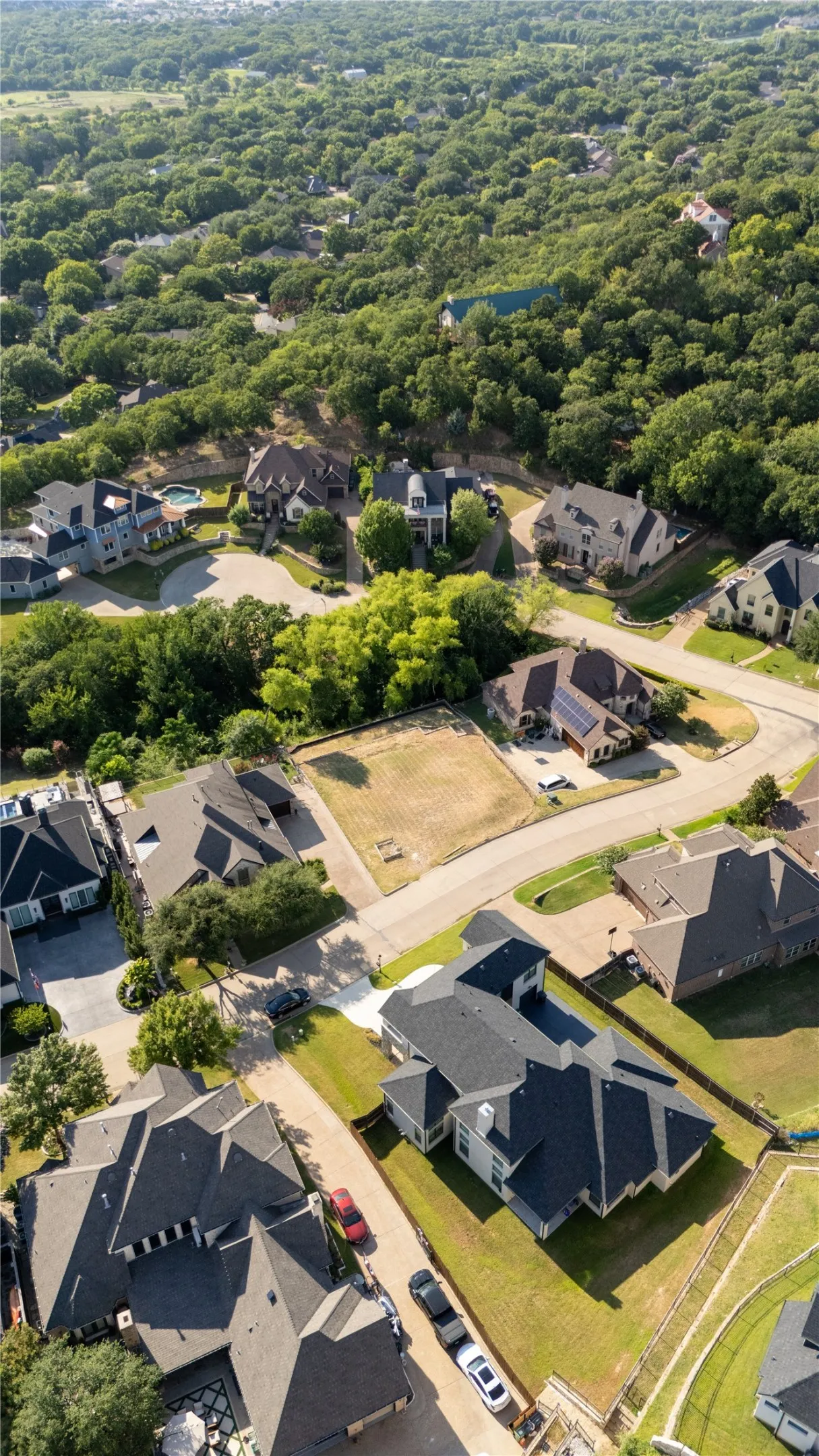Expansive wooded surroundings featuring multiple residential properties with varied architectural styles and dark shingle roofs