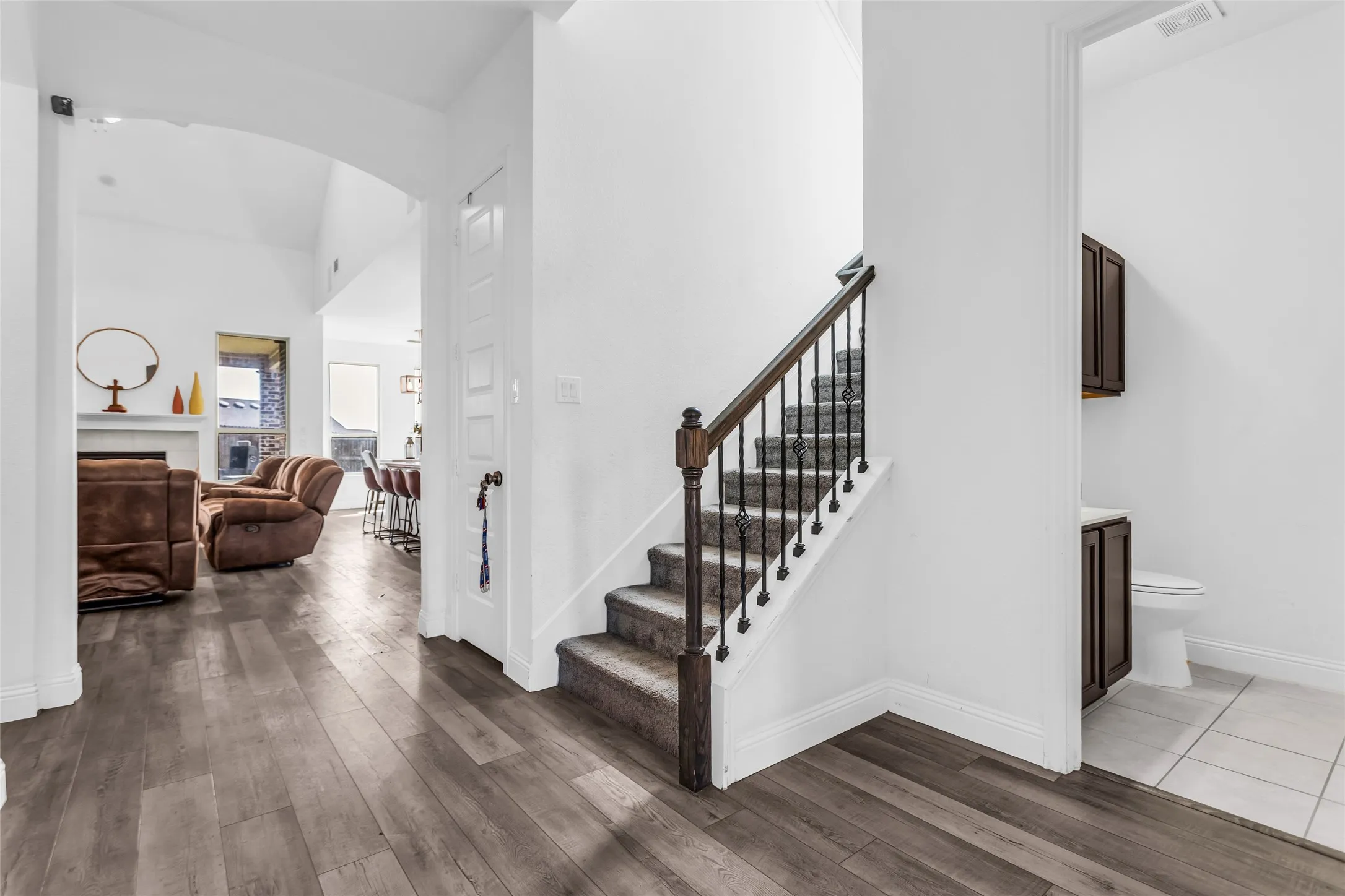 Staircase featuring wood finished floors, arched walkways, and a fireplace