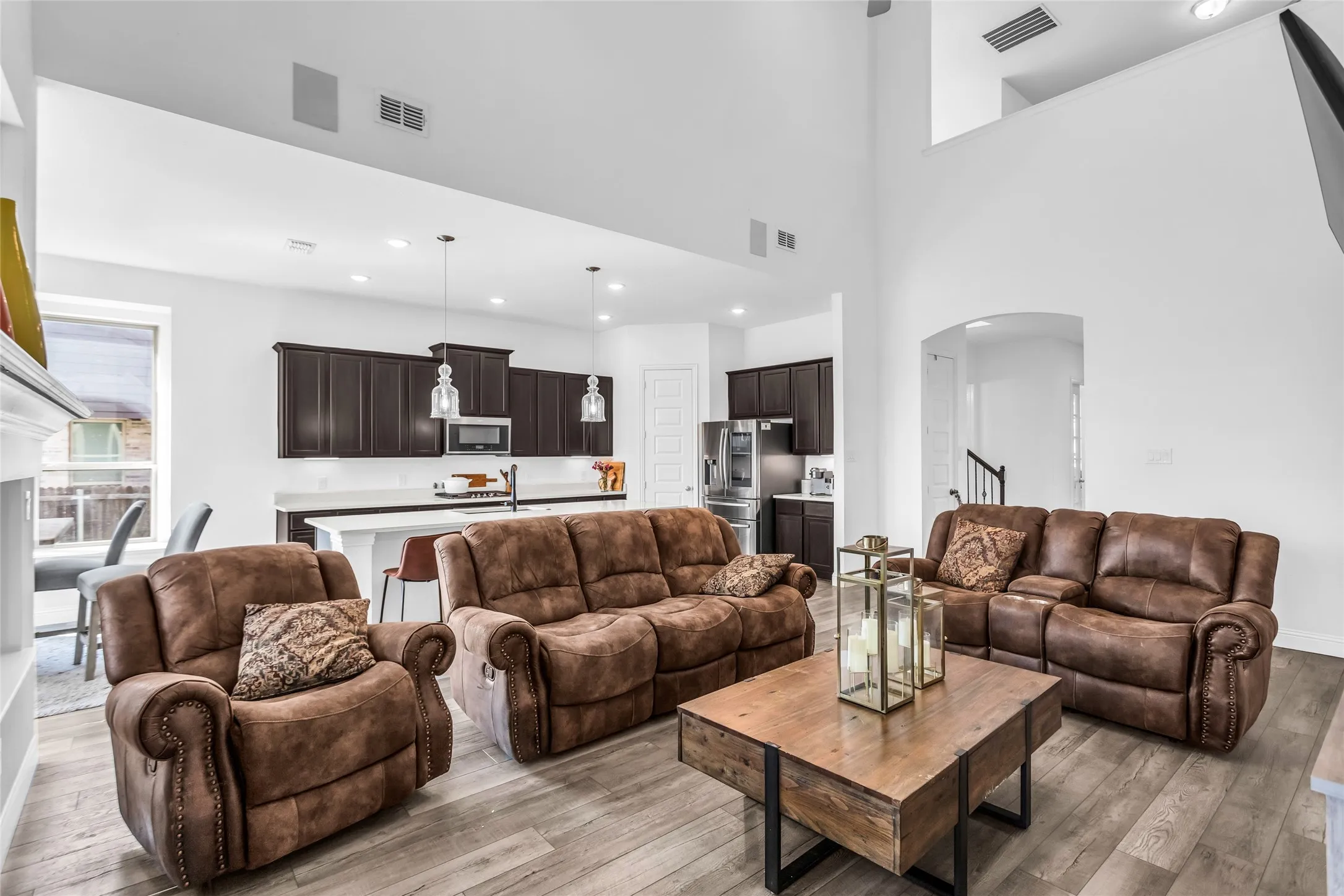 Living area with arched walkways, light wood-style flooring, recessed lighting, and a high ceiling