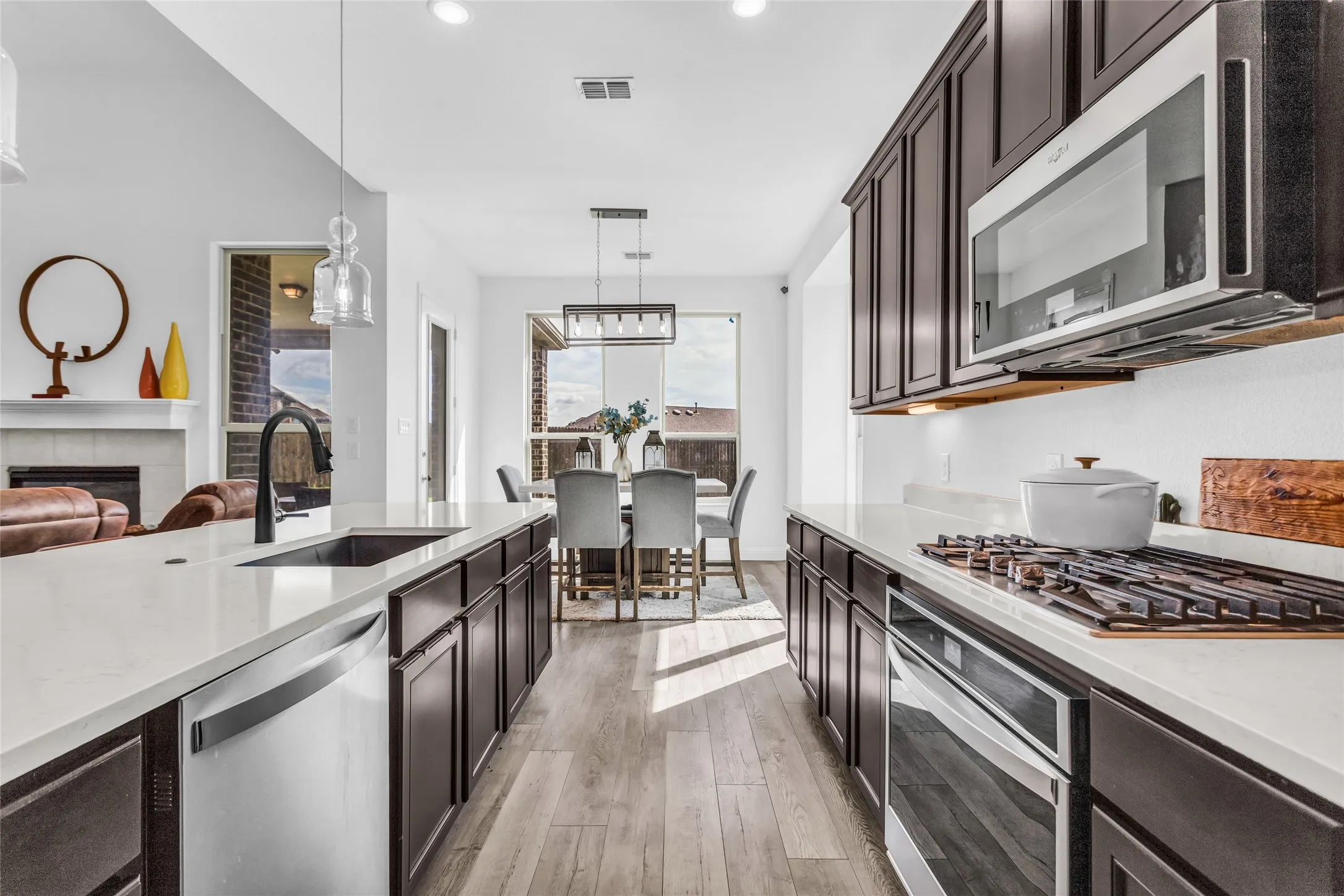 Kitchen featuring light stone countertops, appliances with stainless steel finishes, dark brown cabinets, and recessed lighting