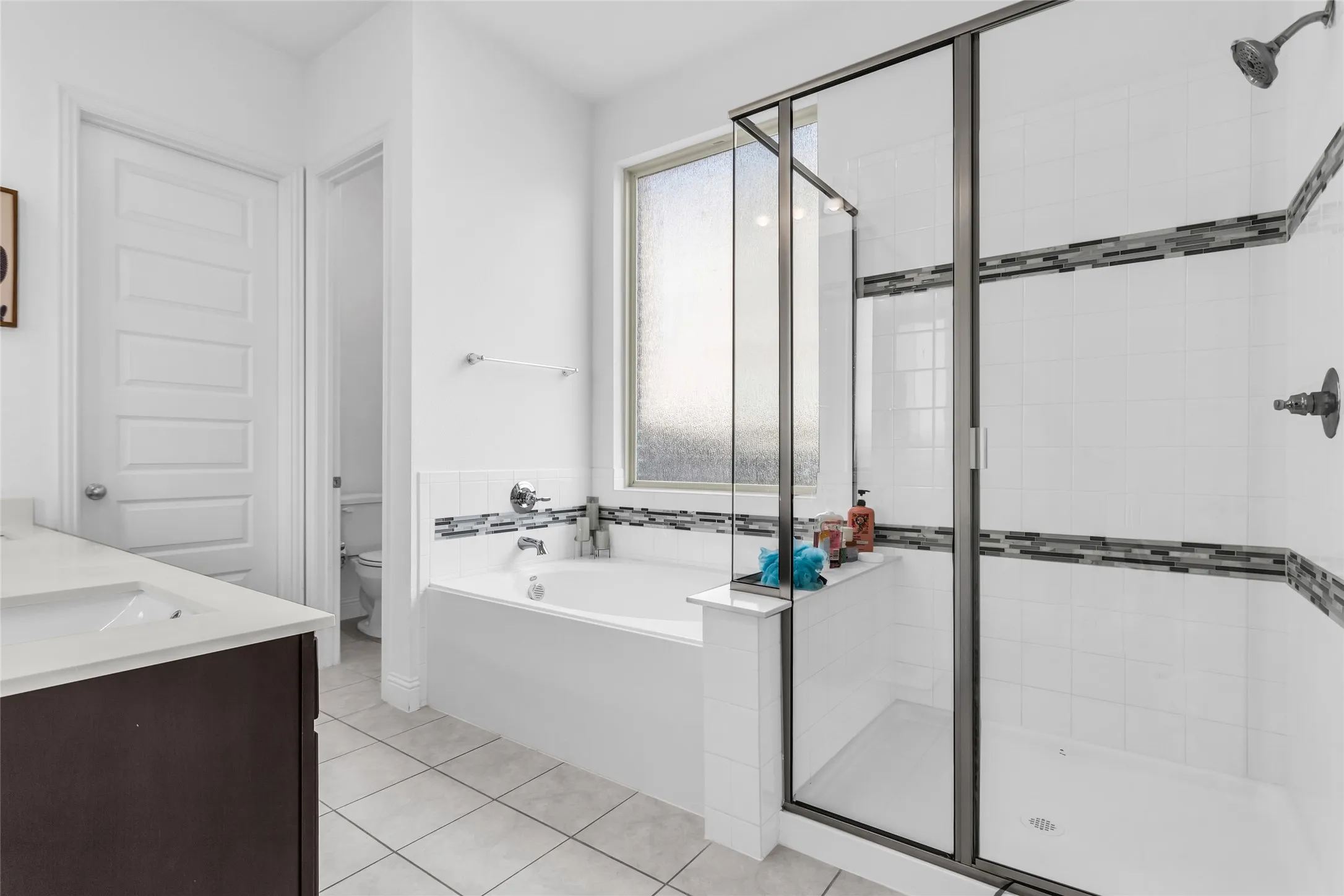 Bathroom with a shower stall, a garden tub, vanity, and light tile patterned flooring