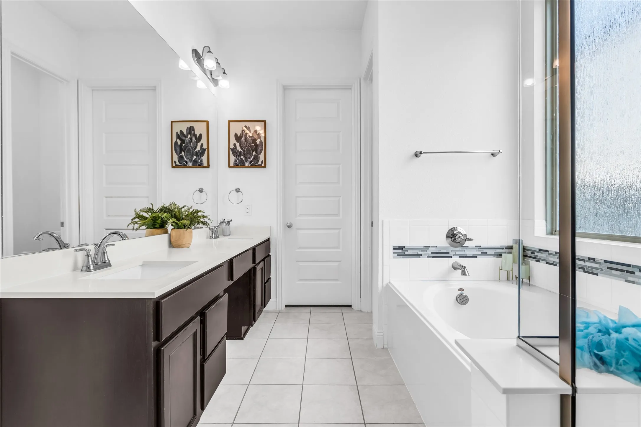 Bathroom featuring light tile patterned floors, double vanity, and a bath