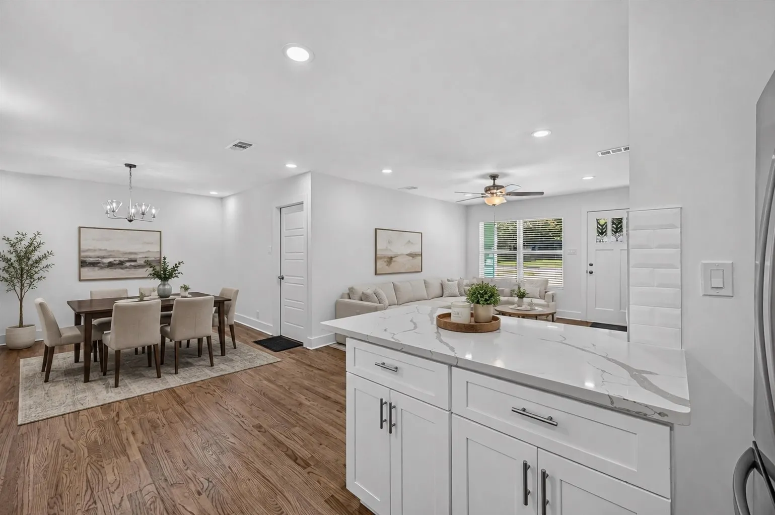 Virtually staged...Kitchen island with a light-toned countertop, white cabinetry, and dark hardware
