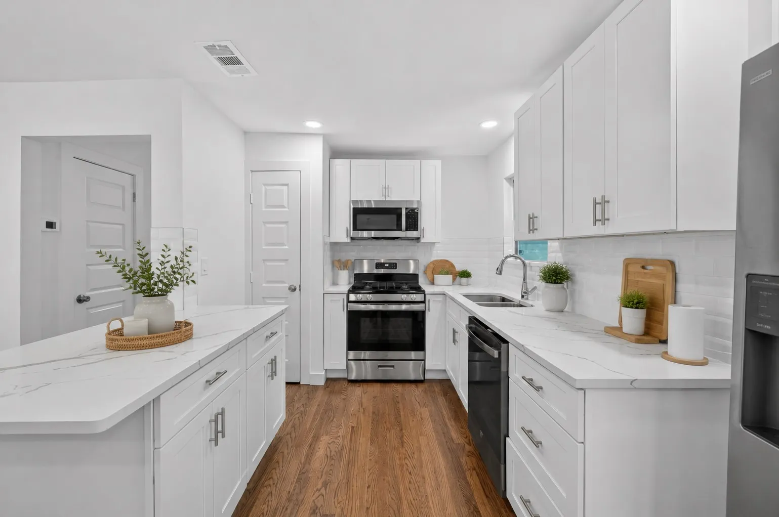 Virtually staged...Bright kitchen featuring white cabinetry, stainless steel appliances, wood-finish flooring, white subway tile backsplash, and light-toned countertops
