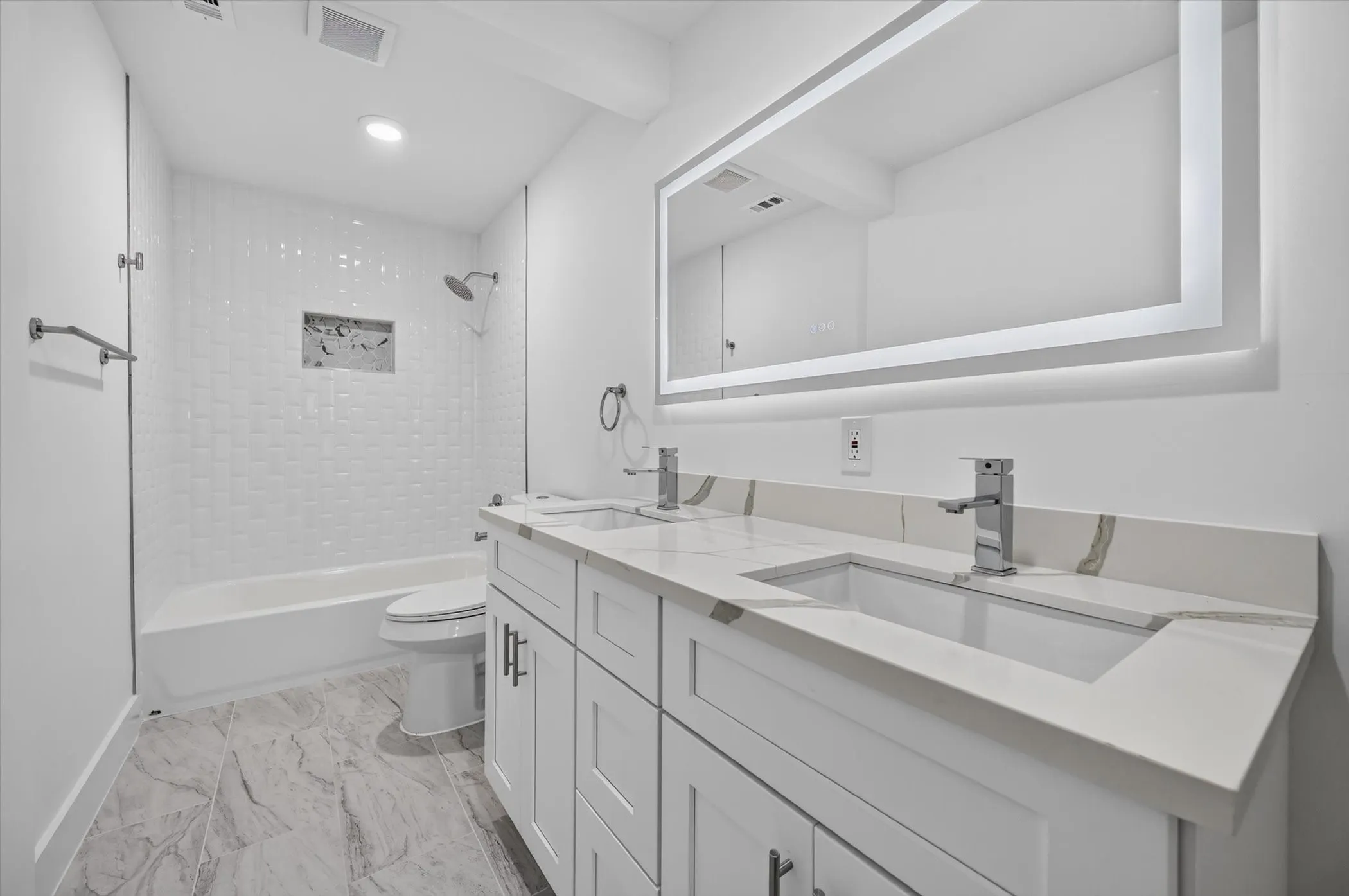 Contemporary bathroom featuring a double vanity with stone countertops, integrated sinks, and chrome fixtures