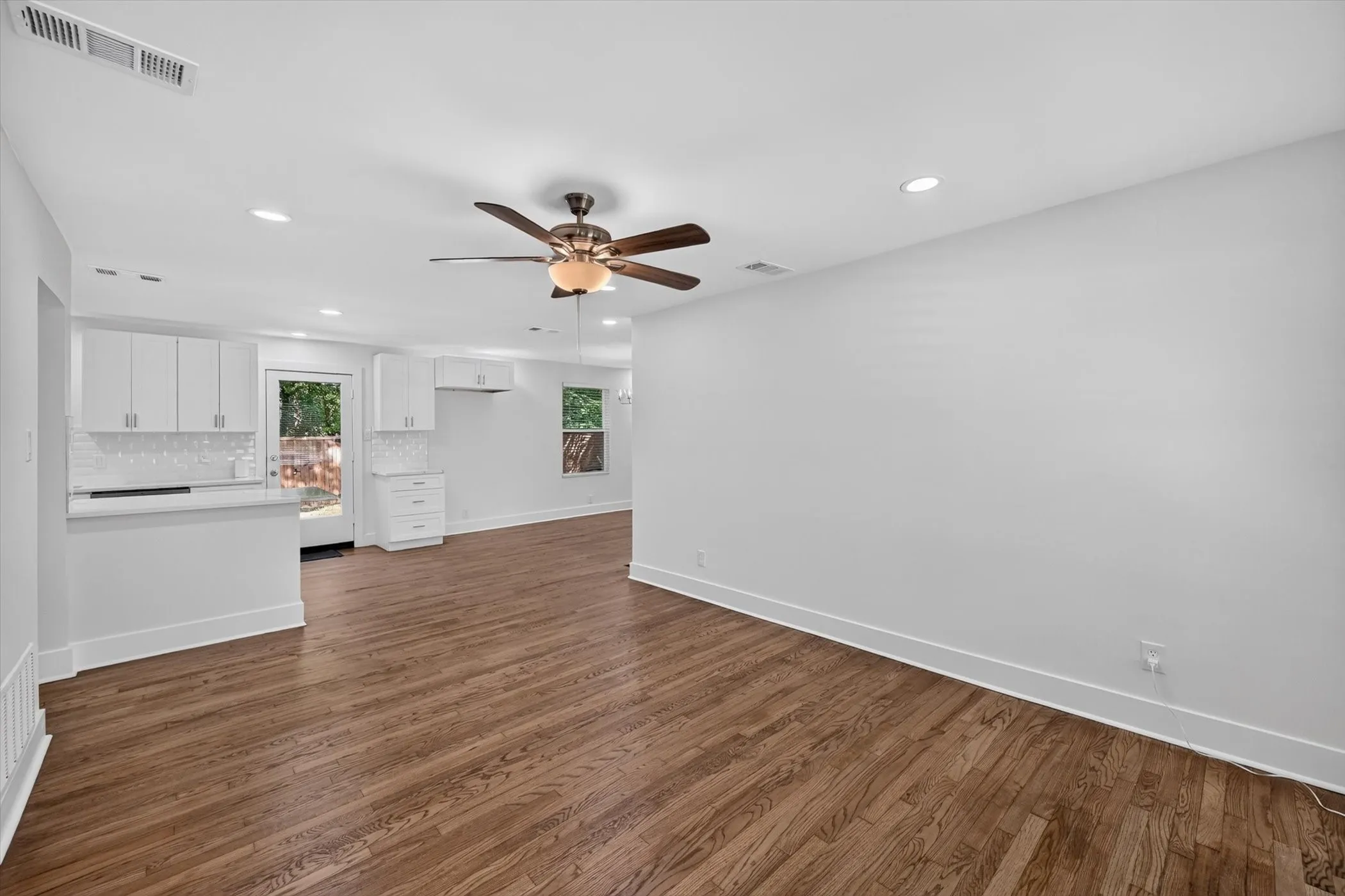 Spacious open-concept living area featuring rich wood-finish flooring, recessed lighting, and a ceiling fan