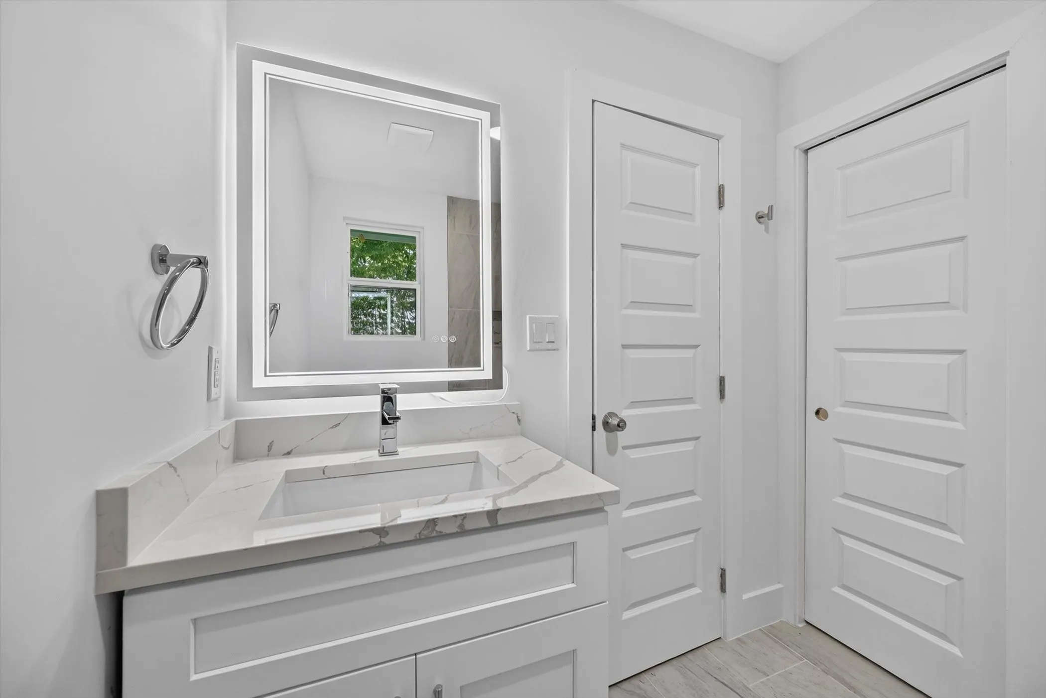 Modern bathroom vanity featuring a rectangular undermount sink, quartz countertop, and integrated LED-lit mirror