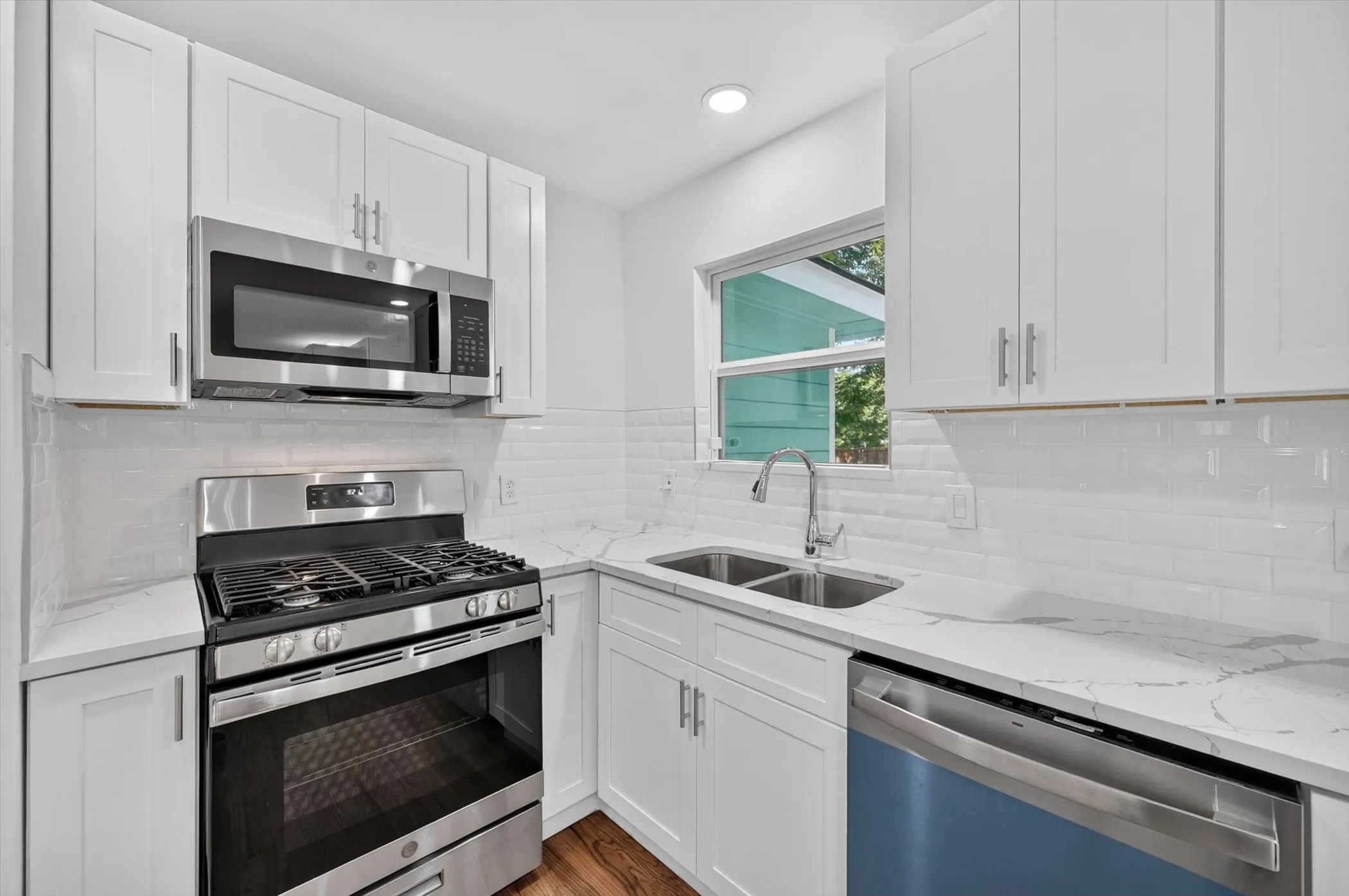 Modern kitchen featuring white shaker cabinetry, stainless steel appliances, white subway tile backsplash, and stone countertops