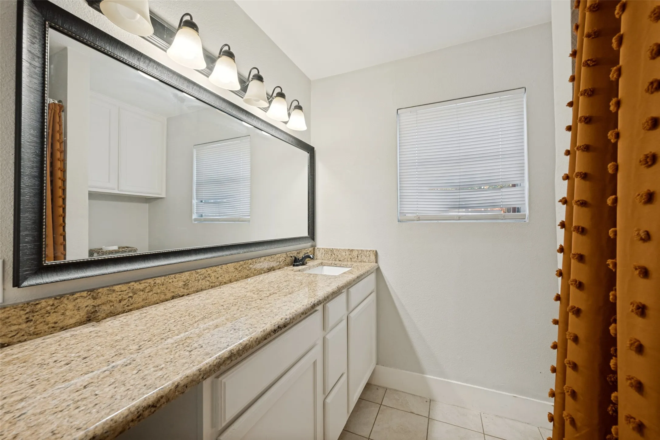 Spacious vanity featuring a light-toned stone countertop, integrated sink, and white cabinetry