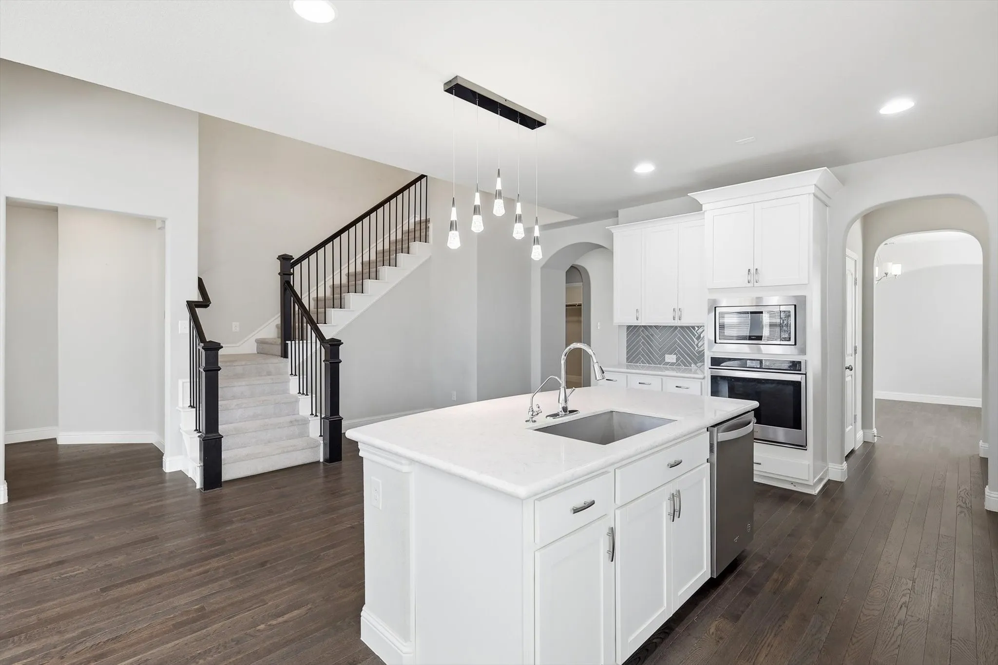 Expansive kitchen island with a built-in sink and pendant lighting, complemented by stainless steel appliances