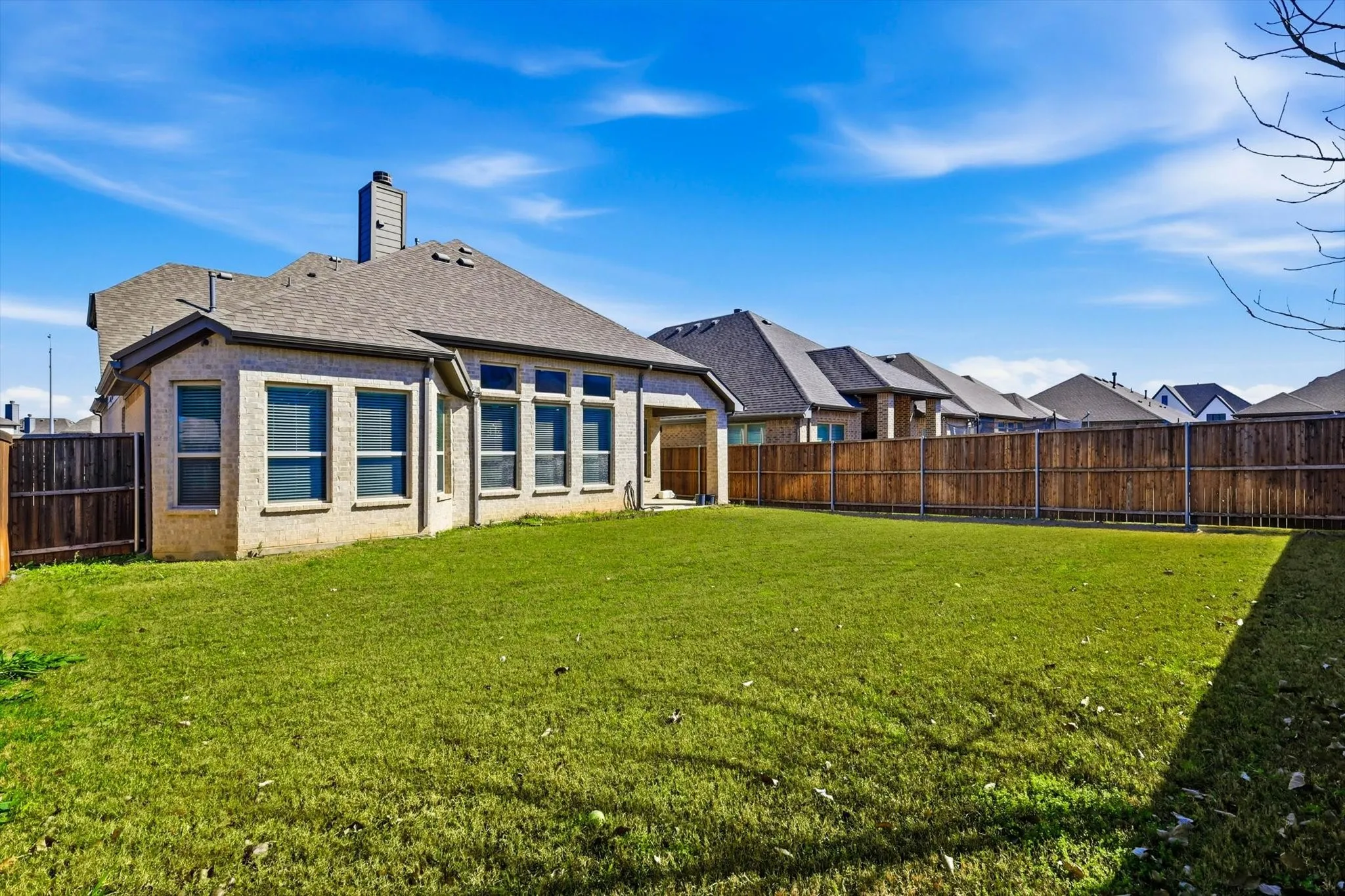 Expansive green lawn with a full privacy fence