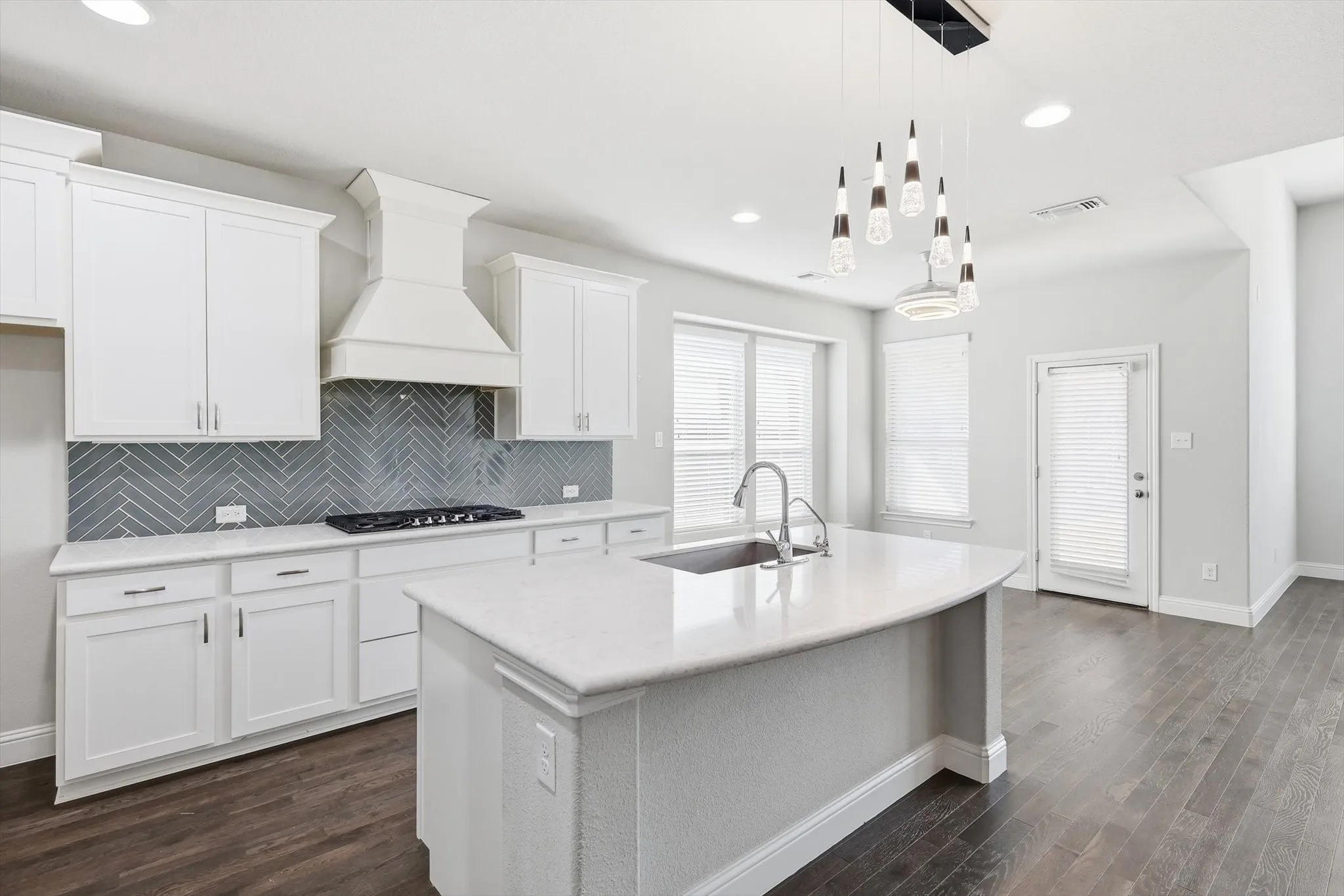 Contemporary kitchen featuring white cabinetry, a built-in range hood, and a herringbone tile backsplash
