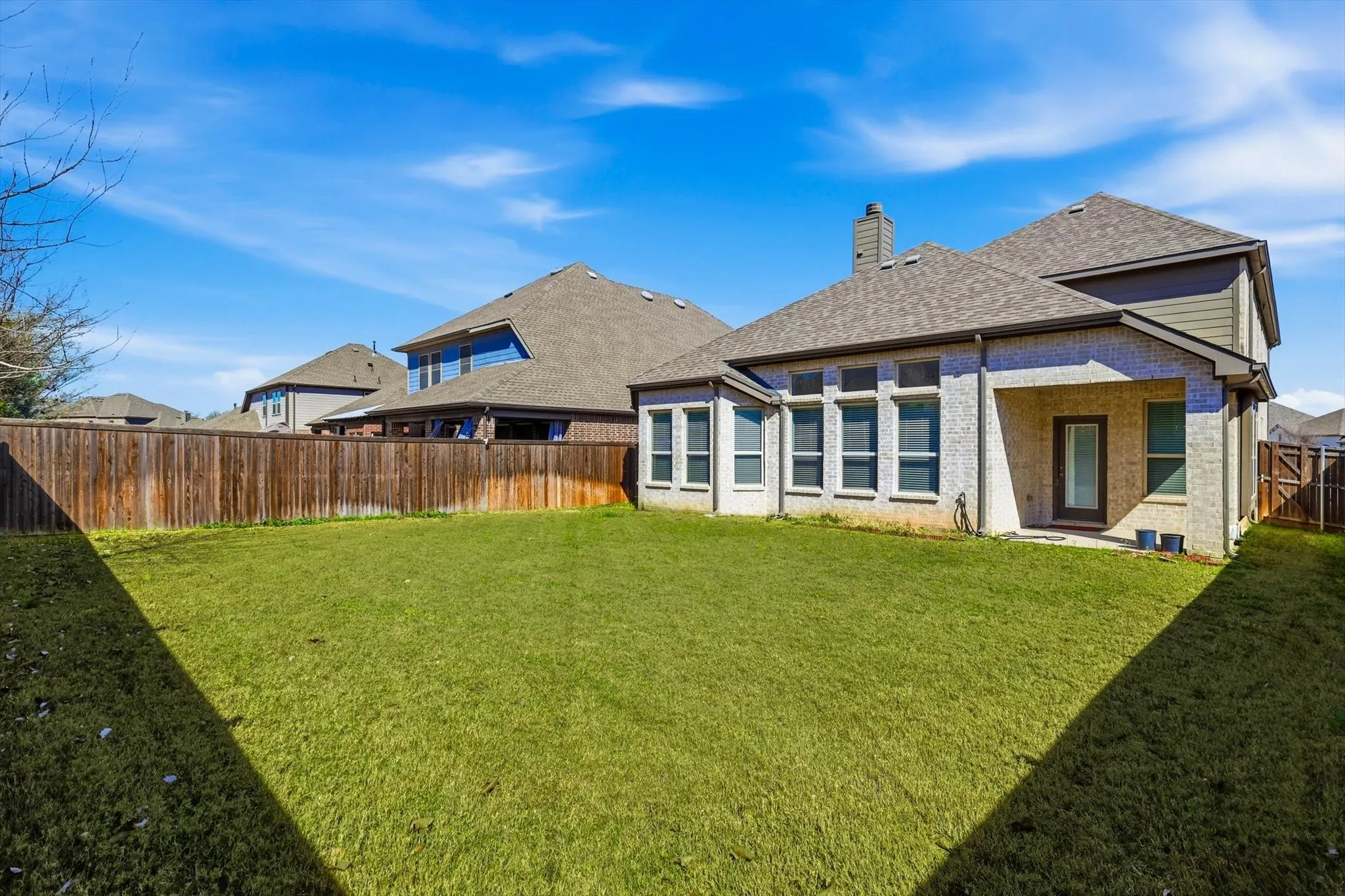 Expansive green lawn with a full privacy fence