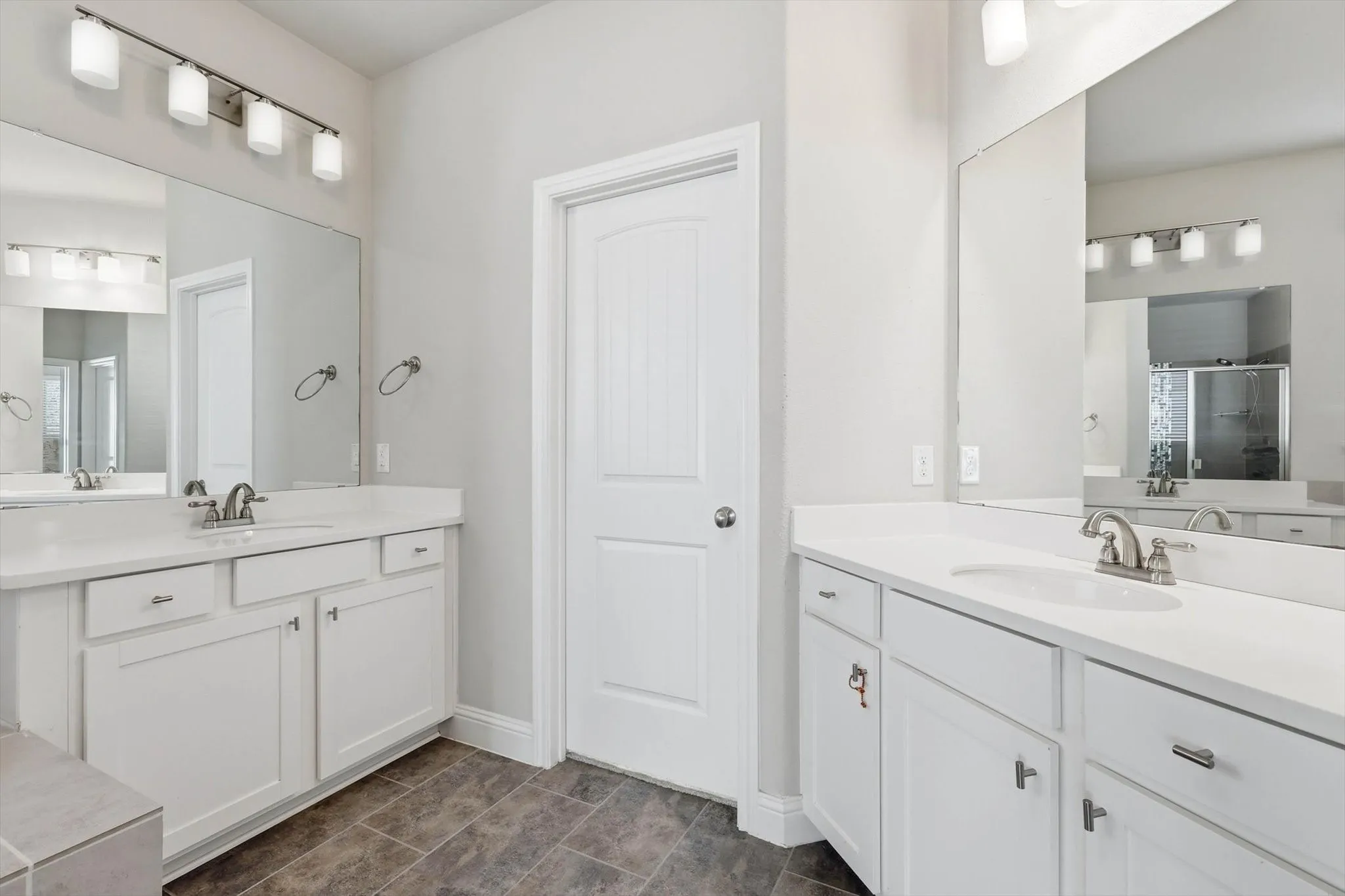 Dual vanities featuring white cabinetry, light-toned countertops, and brushed nickel hardware