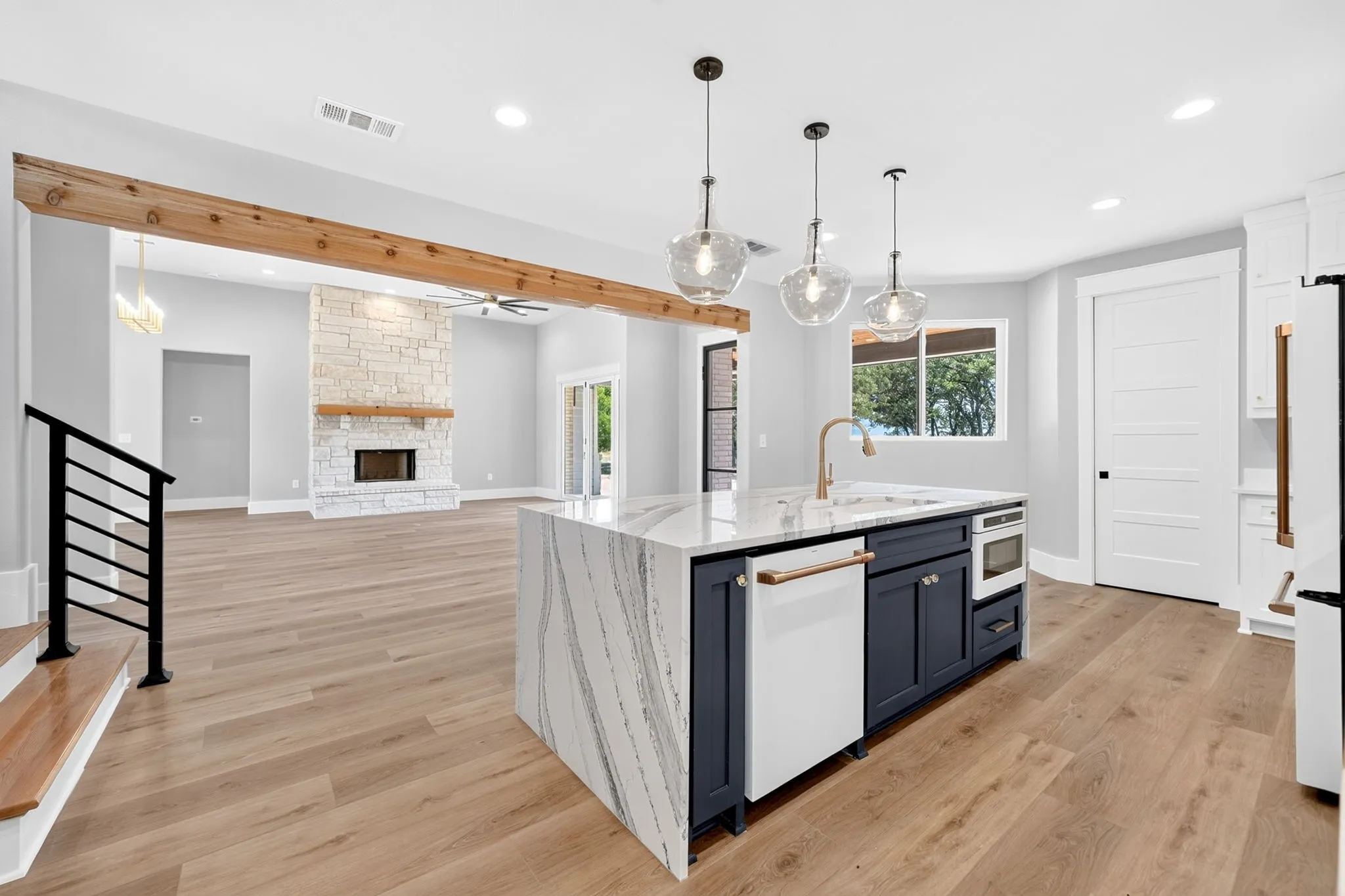 The centerpiece of the gourmet kitchen is the spectacular island, highlighted by a stunning waterfall edge.  An intergraded microwave drawer, and three elegant glass pendent lights.