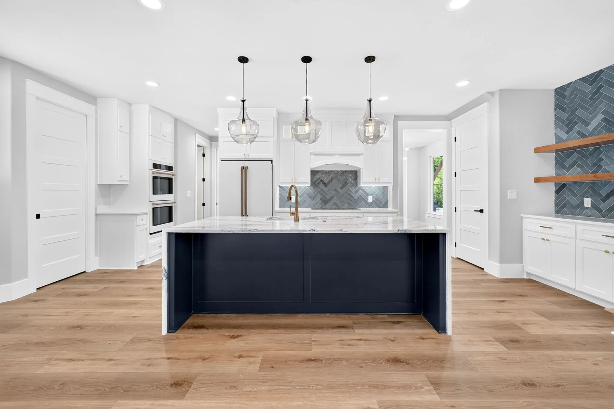 Gourmet chef's kitchen featuring a massive waterfall island with bar seating, crisp shaker cabinetry, and built-in stainless high end Cafe appliances.