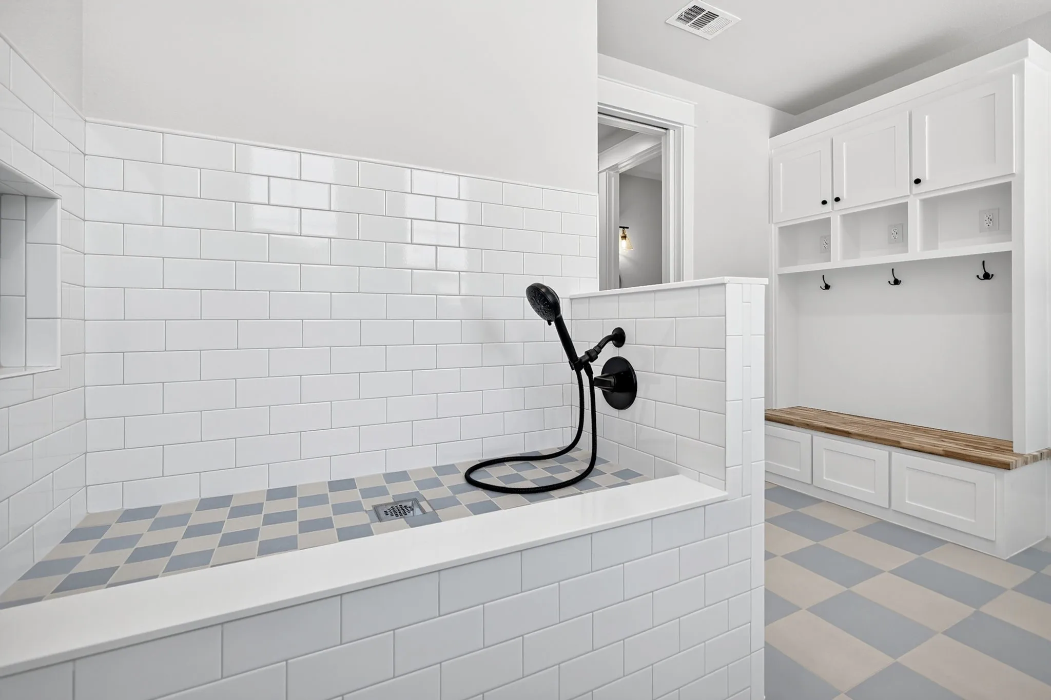 The ultimate mudroom entry, thoughtfully designed with custom storage built-ins and a dedicated, tiled pet/dog wash station for effortless cleanup.