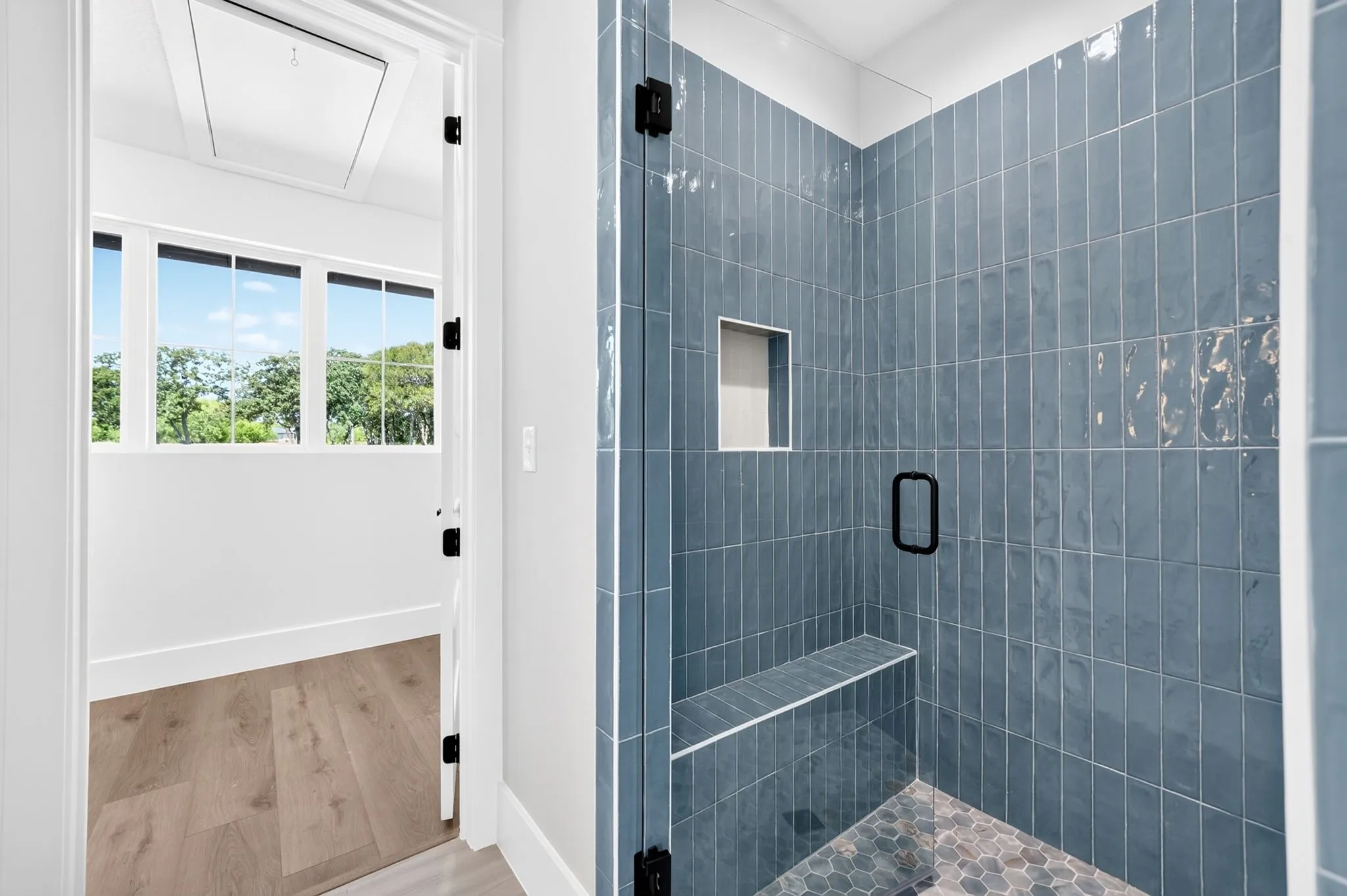 Oversized custom walk-in shower showcasing spectacular tile work, a built-in seating bench and seamless glass enclosure.