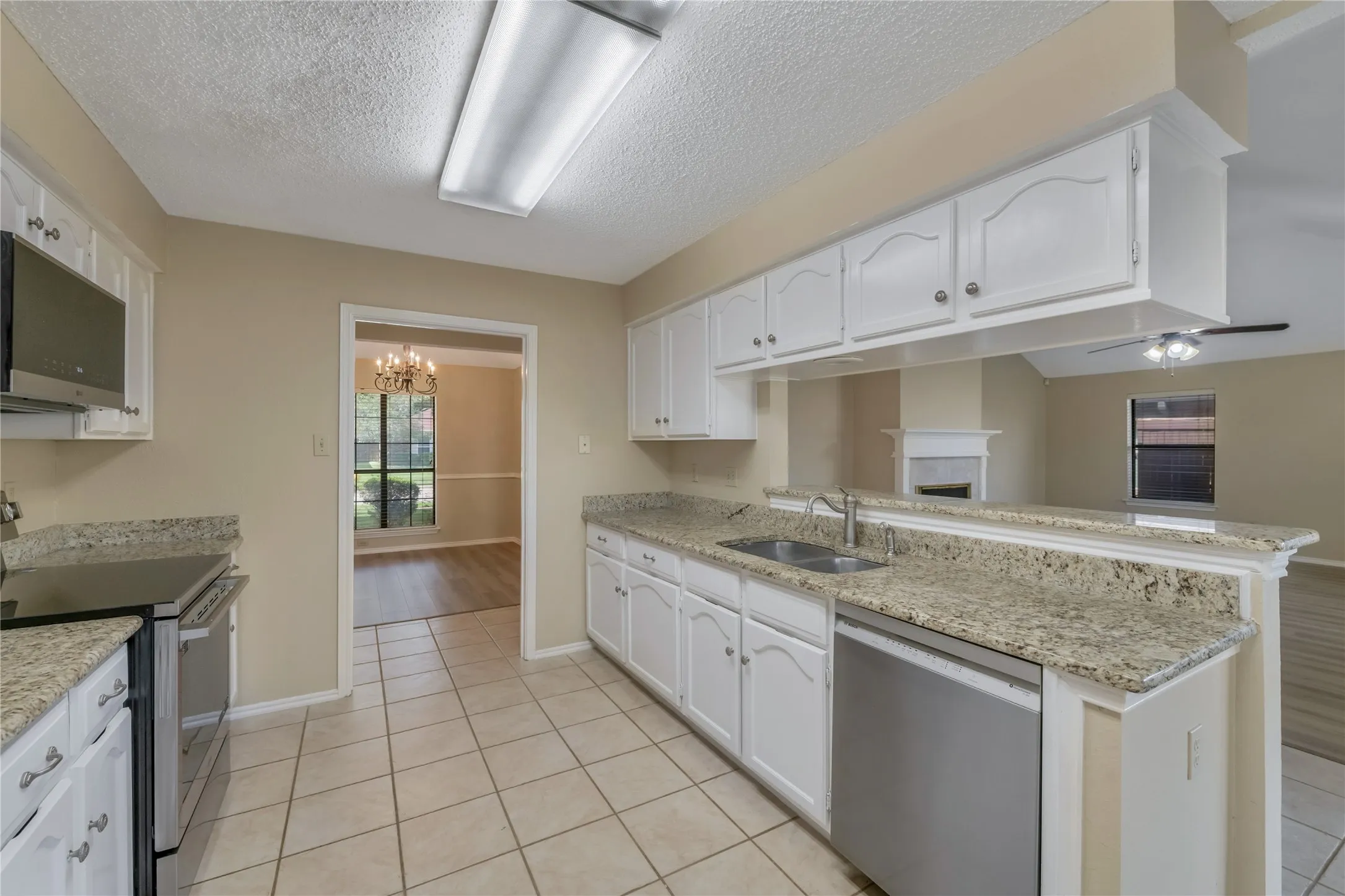 Kitchen featuring white cabinetry, light-toned countertops, tile flooring, and stainless steel appliances