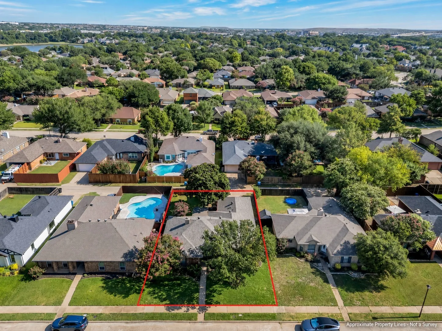 Aerial view showcasing a residential property with a central home, an expansive green lawn, and mature trees