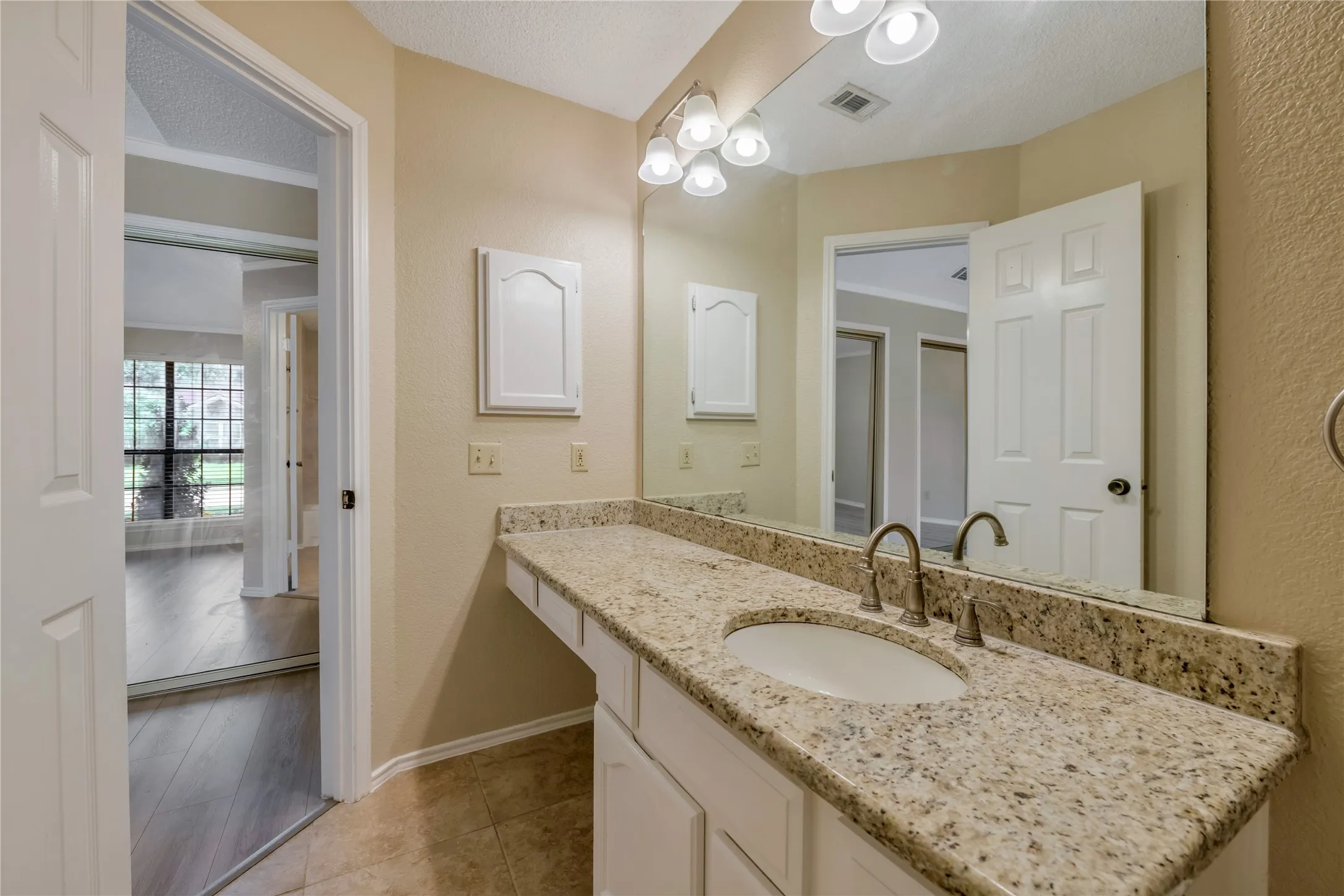 Master Bathroom vanity featuring a light-colored speckled countertop, white cabinetry, undermount sink, and a brushed nickel faucet