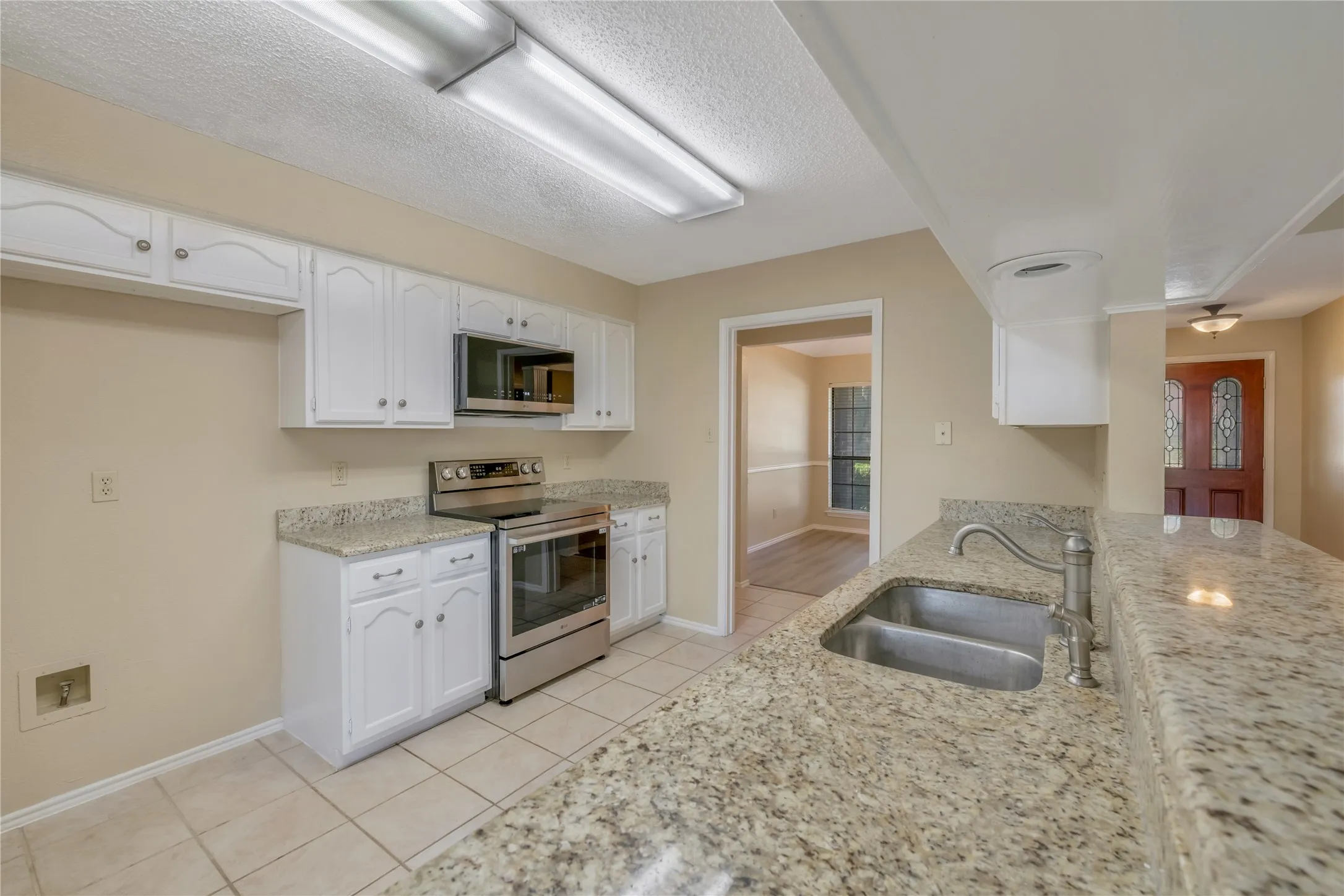 Kitchen featuring white cabinetry, stainless steel appliances, granite countertops, and a dual basin sink with a gooseneck faucet