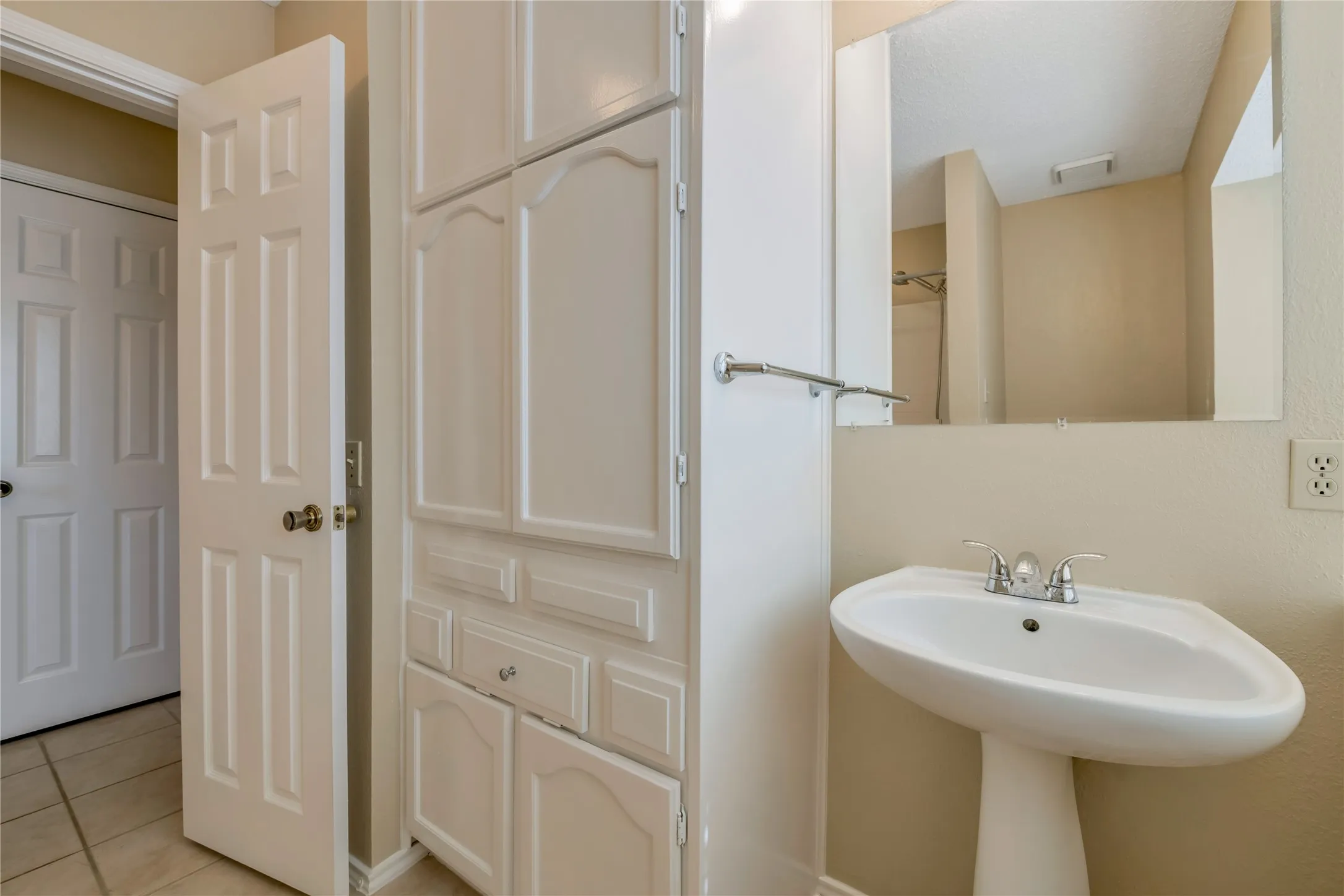Second Bath Pedestal sink with chrome faucet, integrated mirror, and extensive built-in white cabinetry featuring paneled doors and drawer fronts