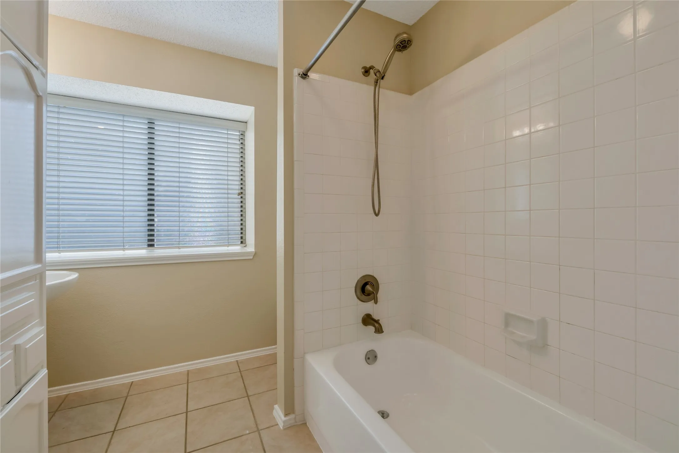 Second Bath White tiled shower and bathtub combination featuring bronze-finish fixtures
