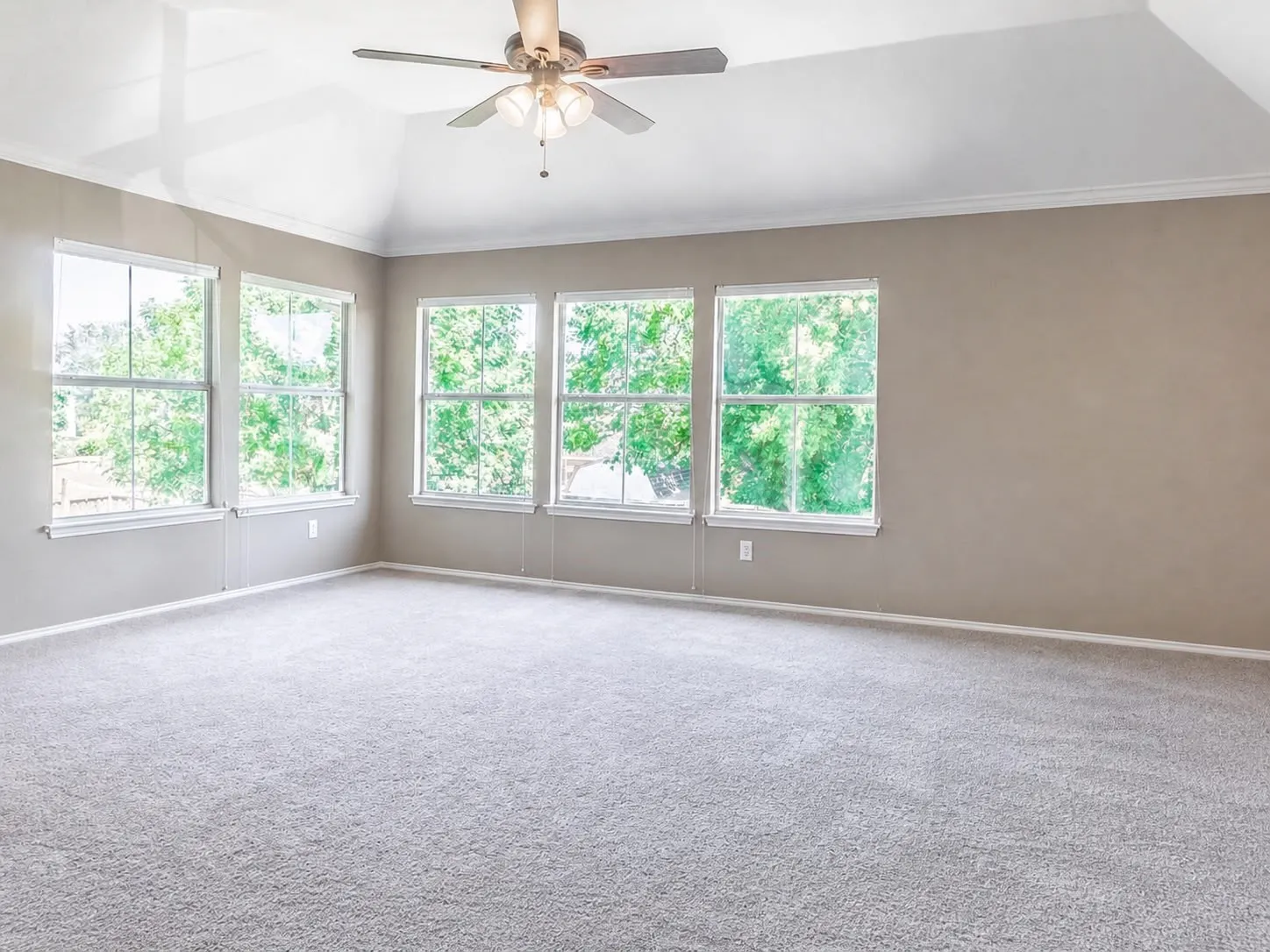 Spacious room featuring vaulted ceilings, light-colored carpeting, and a ceiling fan with integrated​​‌​​​​‌​​‌‌​‌‌​​​‌‌​‌​‌​‌​​​‌​​ lighting