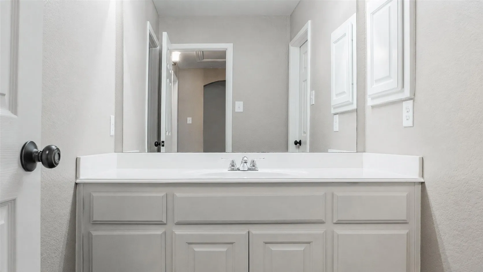 Vanity with a white countertop and integrated sink, complemented by a large wall-mounted mirror