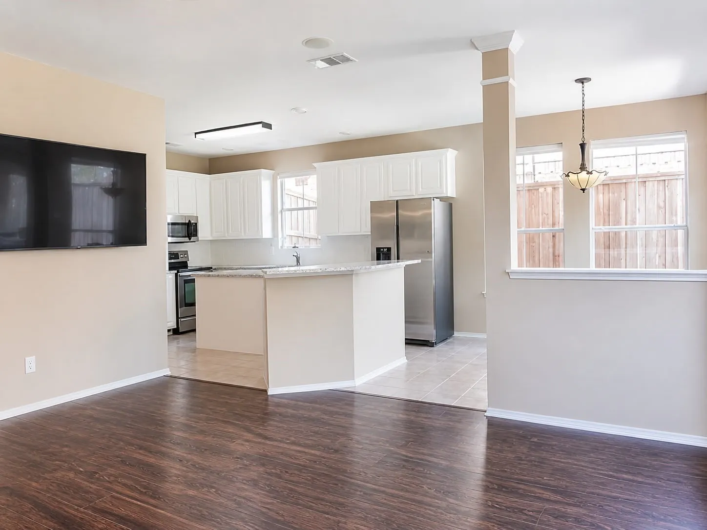 Open-concept kitchen and living area featuring wood-finish flooring, white cabinetry, light countertops, and stainless steel appliances