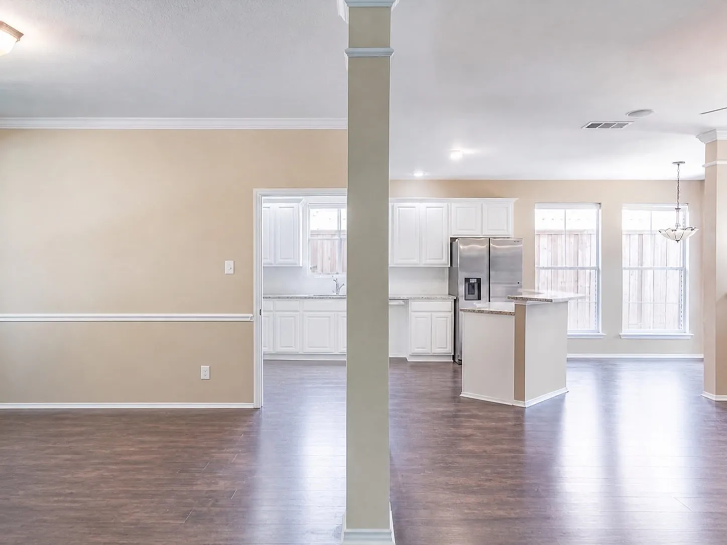 Expansive open-concept space featuring wood-finish flooring, crown molding, and wainscoting