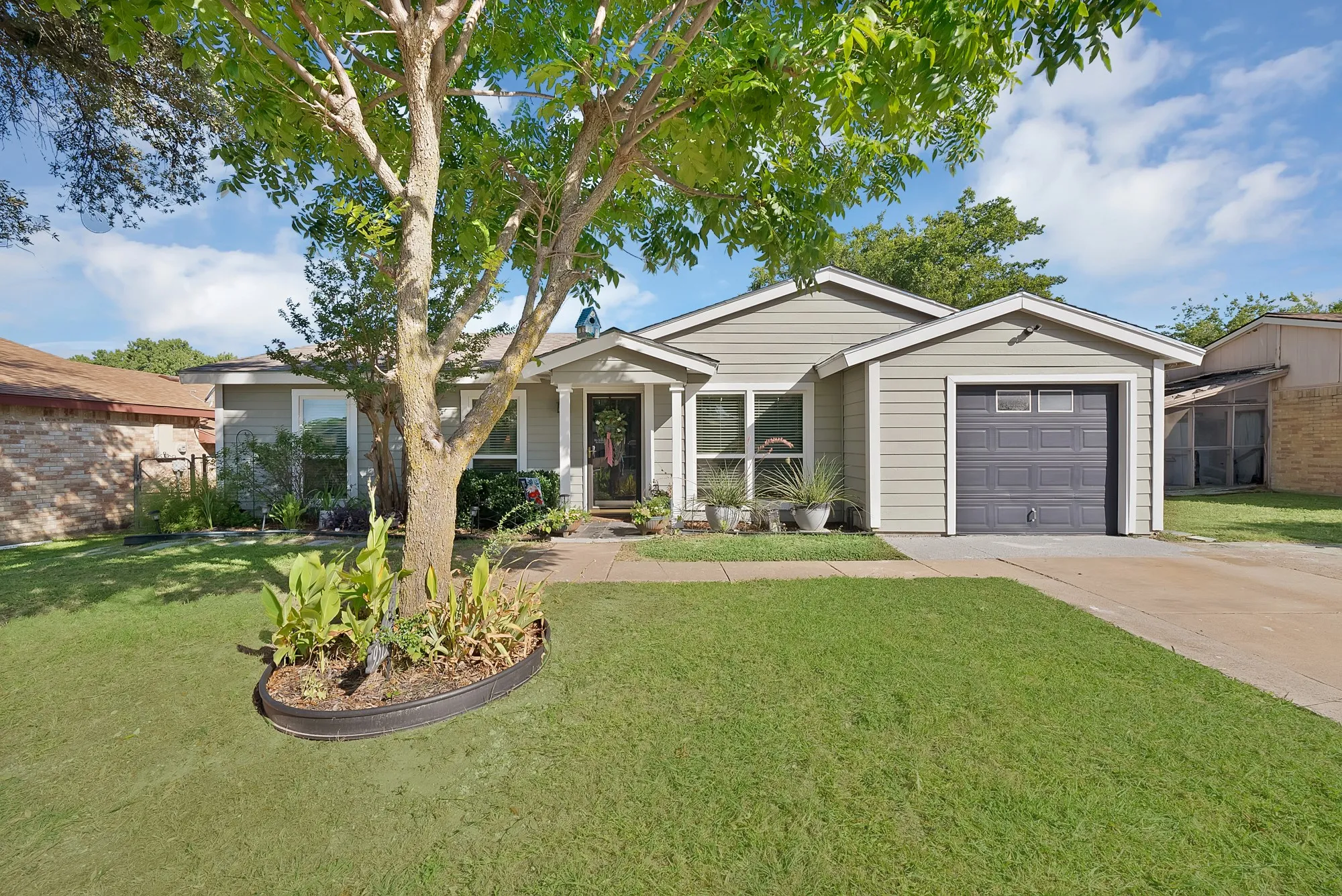 Single-story residence featuring light gray siding and a dark gray garage door with windows
