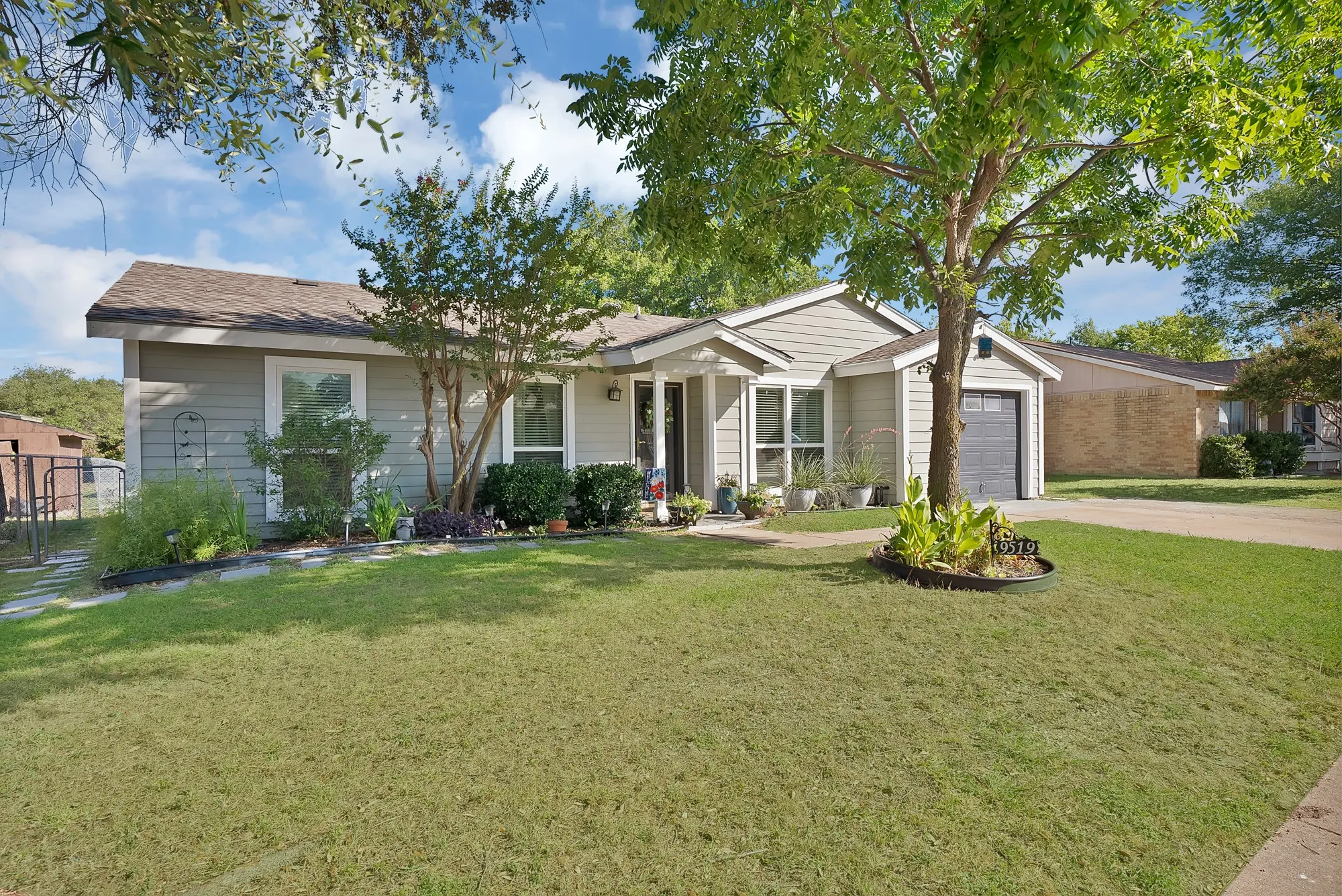 Single-story residence featuring light gray siding, an attached garage with a dark gray door, a brown shingle roof, and a concrete driveway