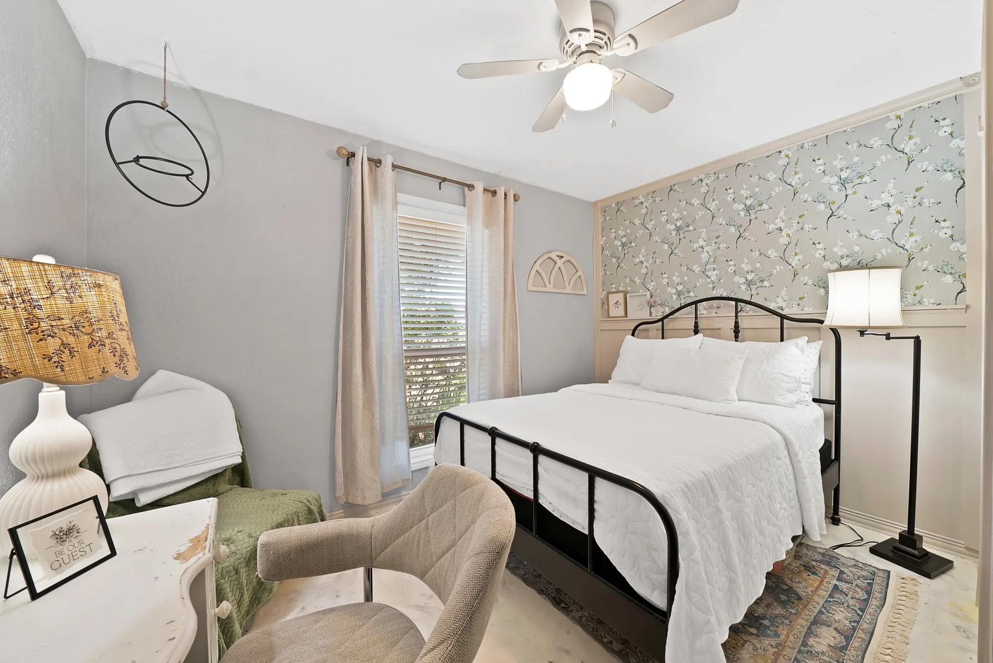Room featuring a ceiling fan with integrated lighting, a window with blinds, and a decorative accent wall with floral wallpaper