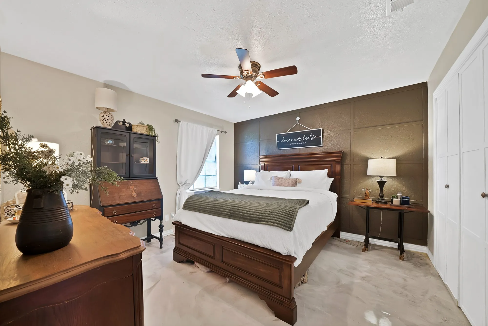 Bedroom featuring a decorative accent wall, ceiling fan with integrated lighting, and carpeted flooring