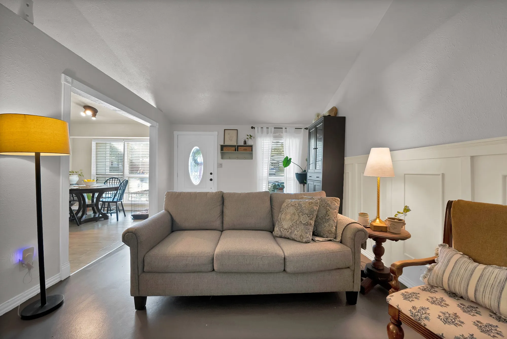 Living area with board and batten wall paneling, wood-finish flooring, and an arched doorway leading to an additional space