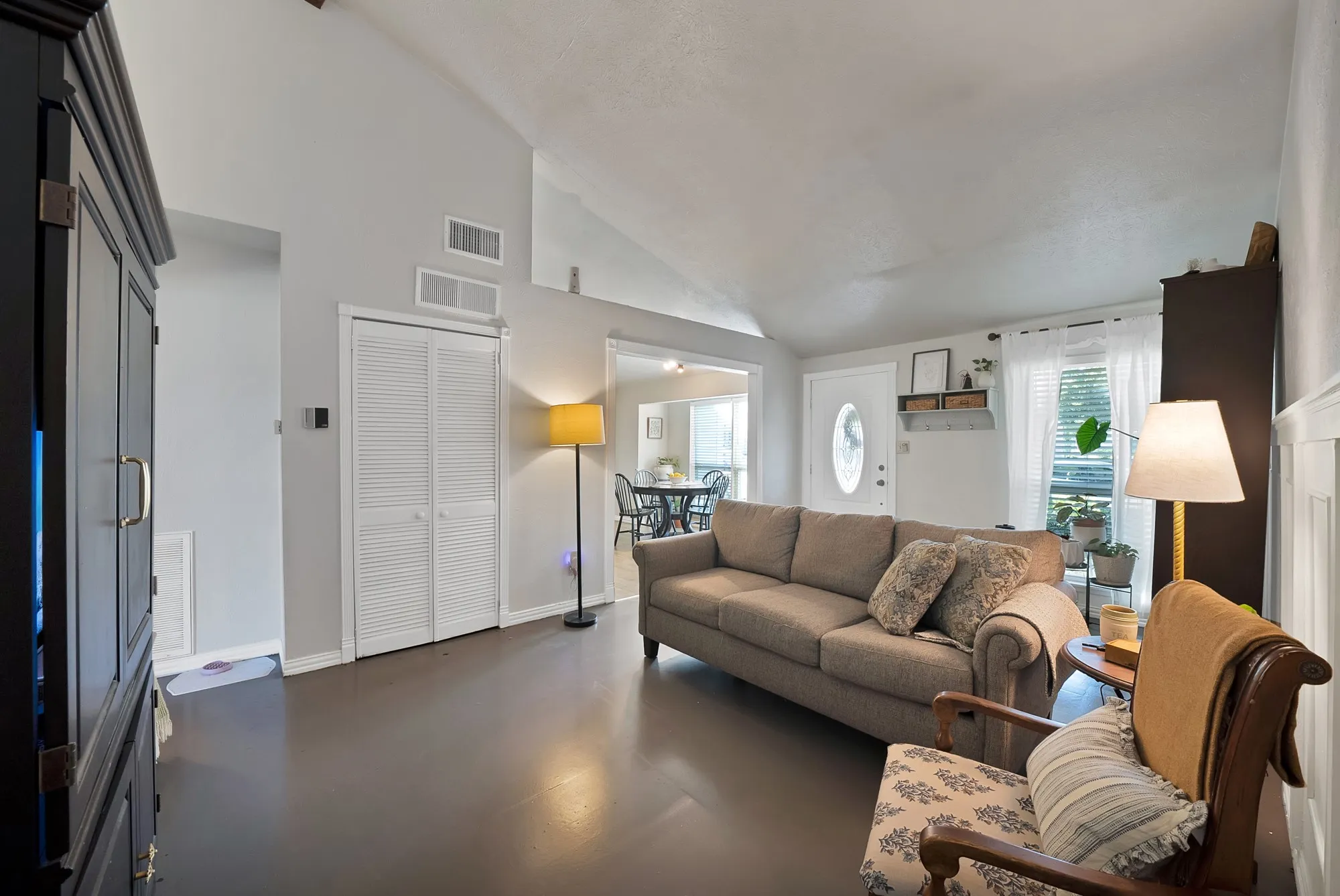 Living area featuring vaulted ceilings, light gray wall paint, and dark wood-finish flooring