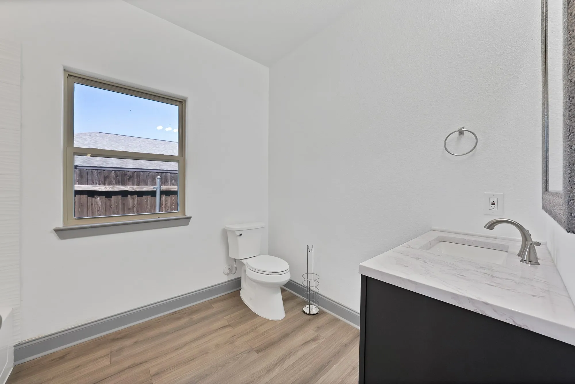 Modern bathroom featuring a single-pane window, wood-finish flooring, and a white toilet