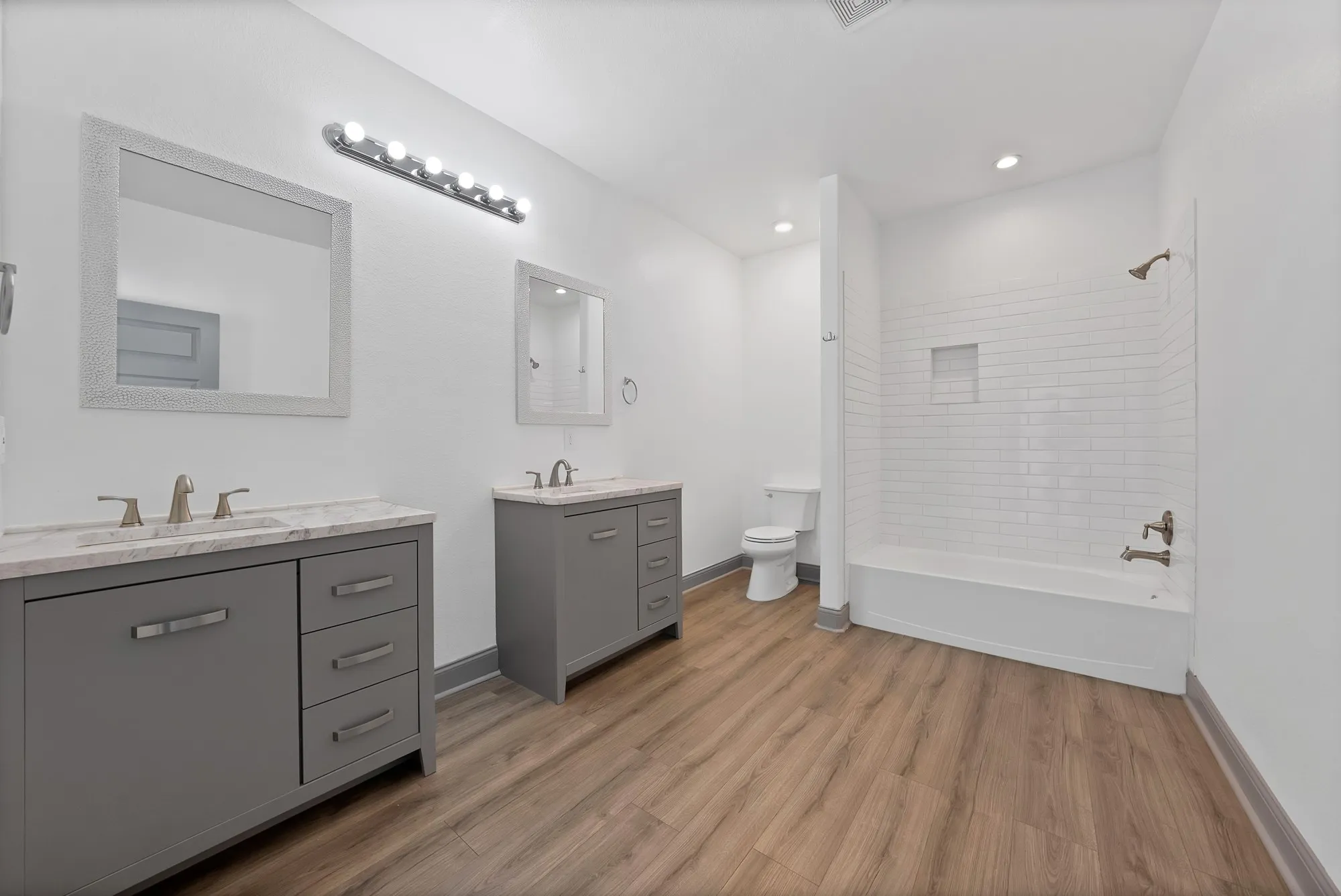 Dual vanity sinks with stone-finish countertops and gray cabinetry